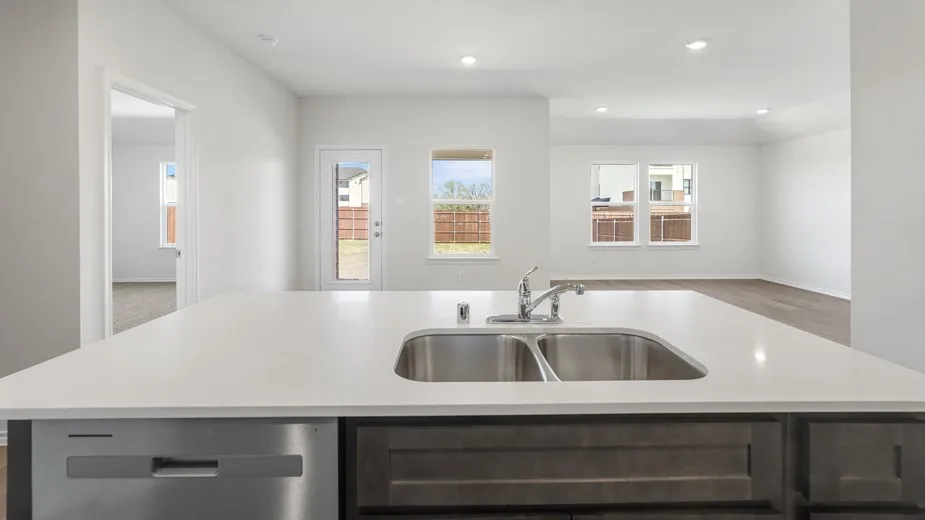 Kitchen island with a dual basin stainless steel sink, stainless steel dishwasher, and dark wood-finish cabinetry