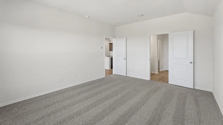 Spacious room featuring neutral carpeting, white walls, and vaulted ceilings