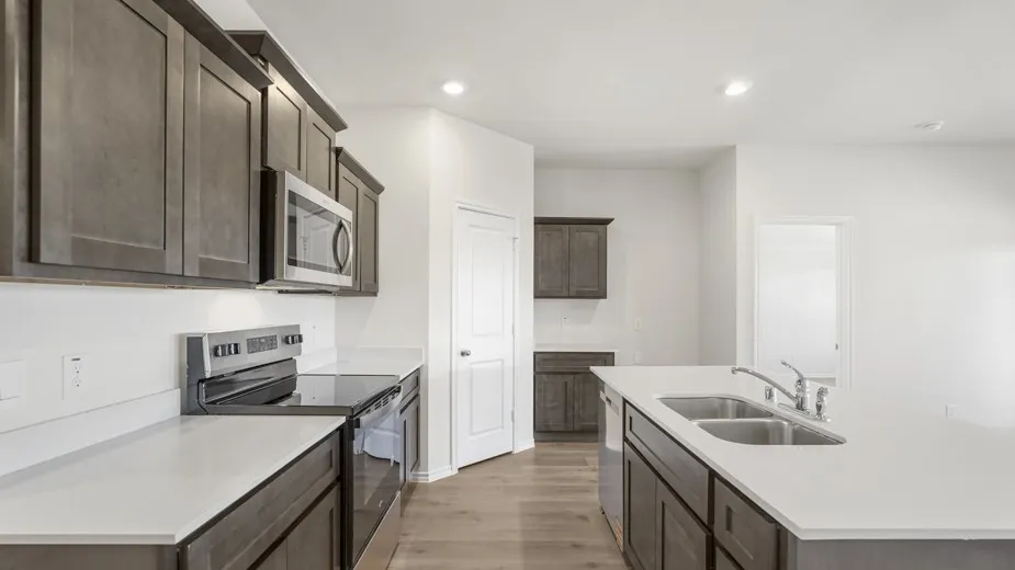 Kitchen featuring wood-finish flooring, white countertops, dark wood-finish cabinetry, stainless steel appliances, and an undermount double basin sink