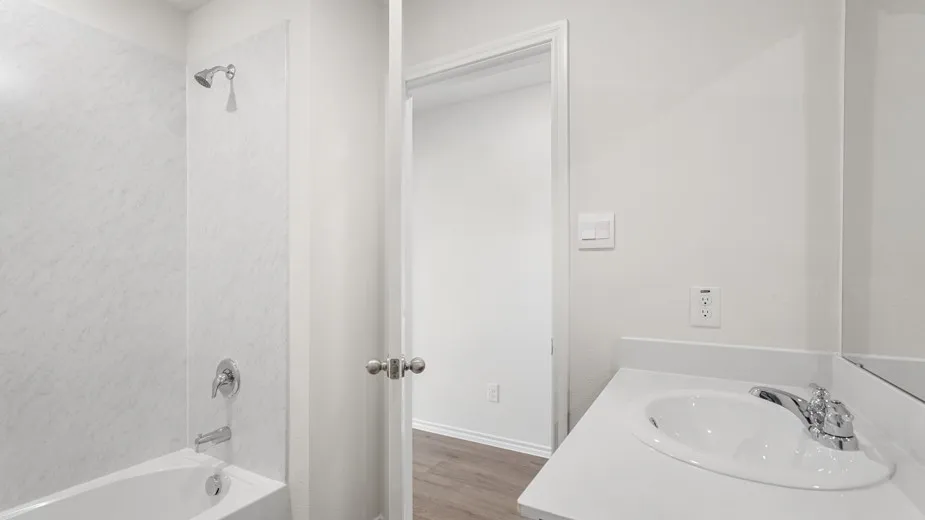 Contemporary bathroom featuring a white bathtub, integrated shower, chrome fixtures, and a vanity with an integrated sink