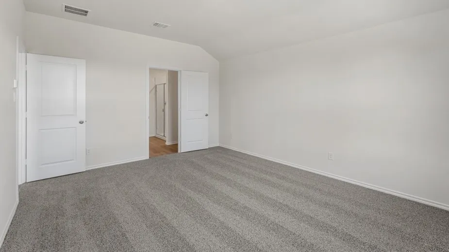 Vaulted ceiling, two paneled doors, light gray carpeting, and light wall finishes