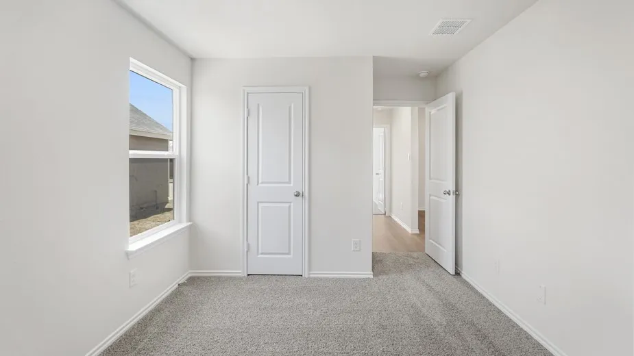 Wall-to-wall carpeting, white interior paint, white trim, white door with silver-tone hardware, and a window with white framing
