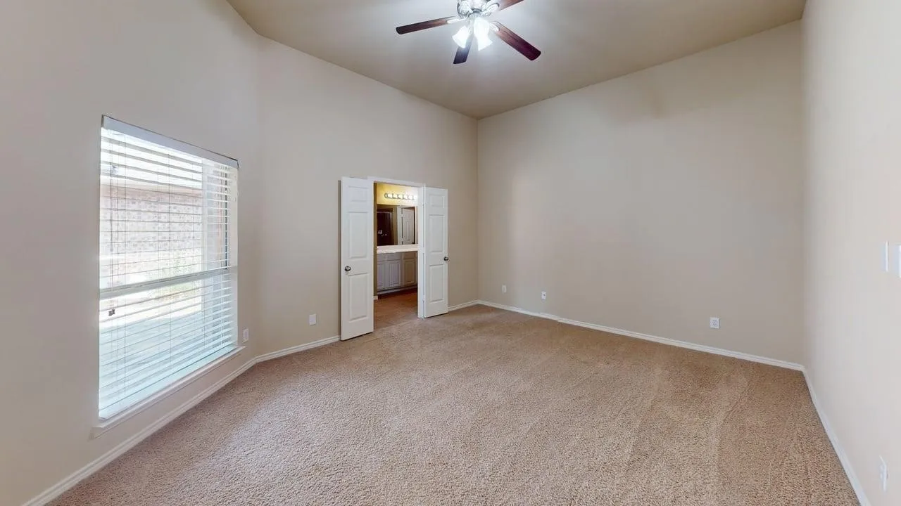 Vaulted ceiling room with neutral carpet flooring and a ceiling fan
