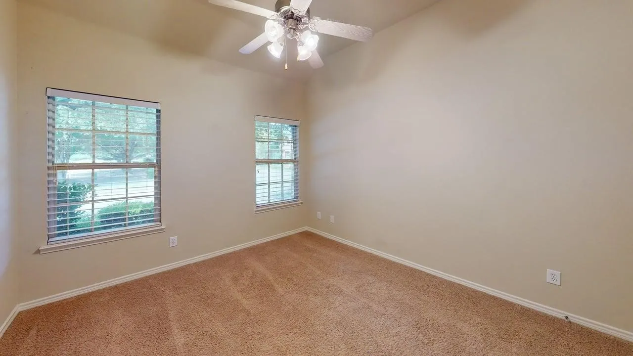 Vaulted ceiling with a ceiling fan, two windows with blinds, and carpet flooring