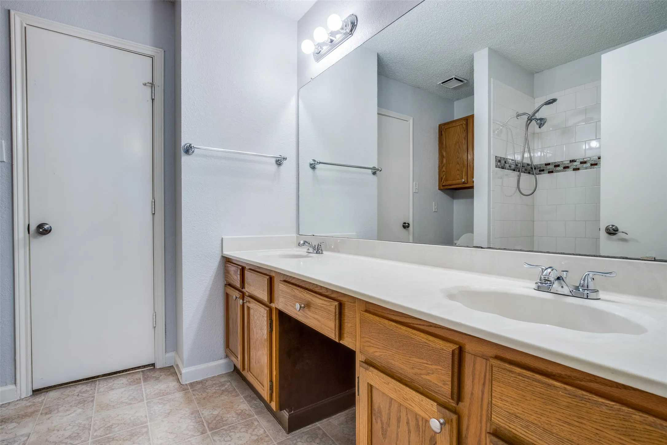 Dual vanity with integrated sinks, wood-finish cabinetry, and a full-width mirror