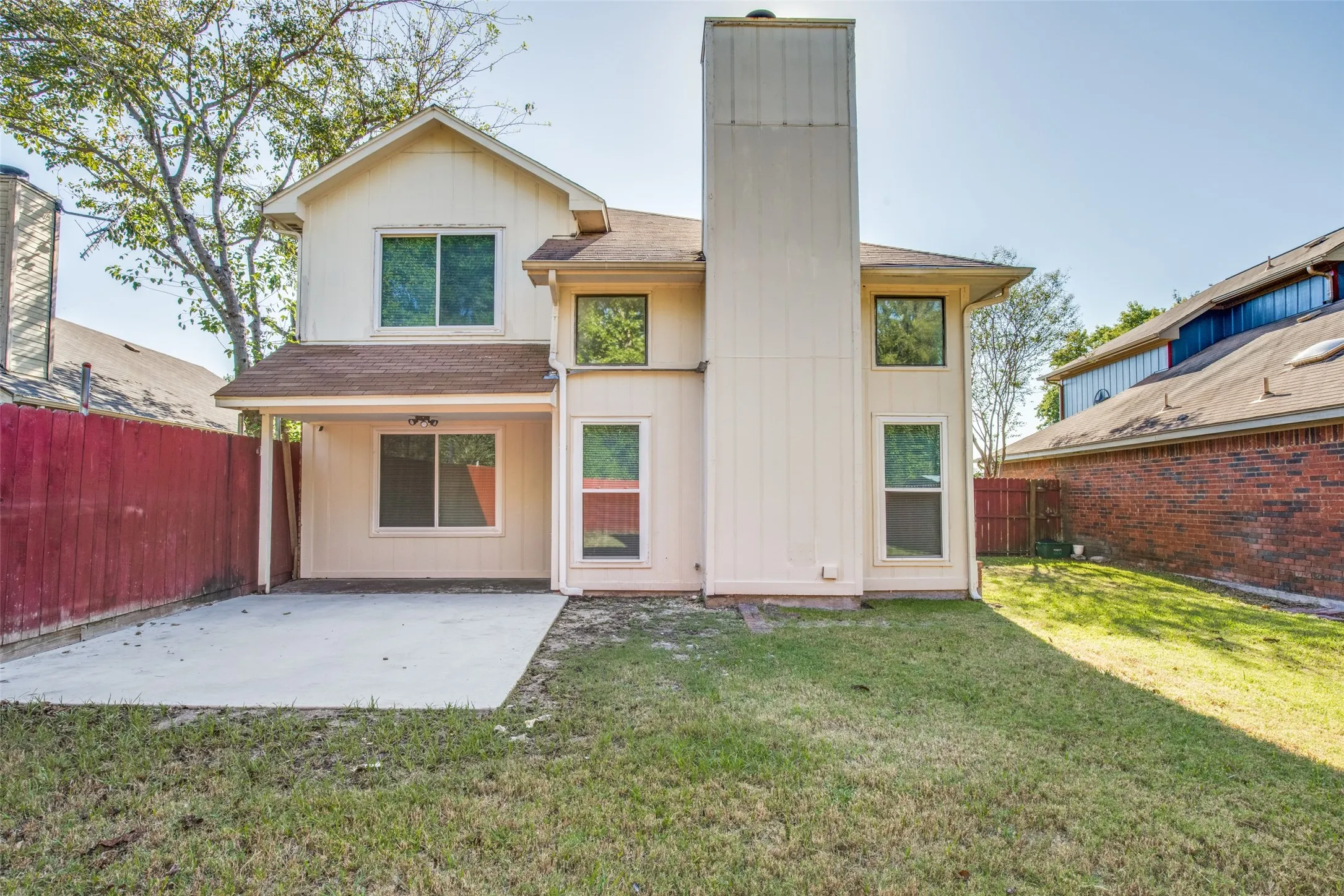 Two-story residence with a covered patio, multiple windows, and a fenced yard