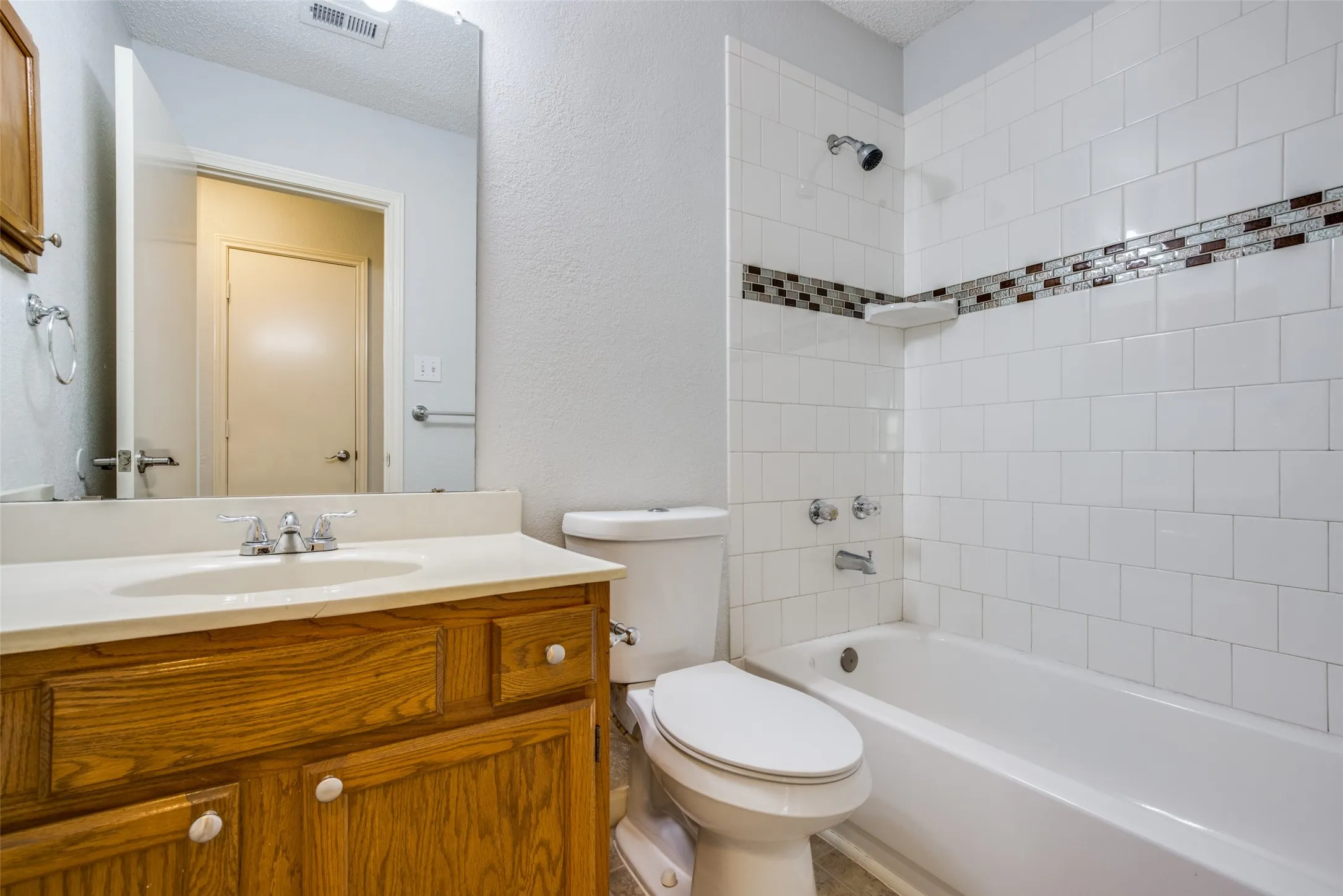 Bathroom featuring a single vanity with wood cabinetry, a built-in sink, and a full-width mirror