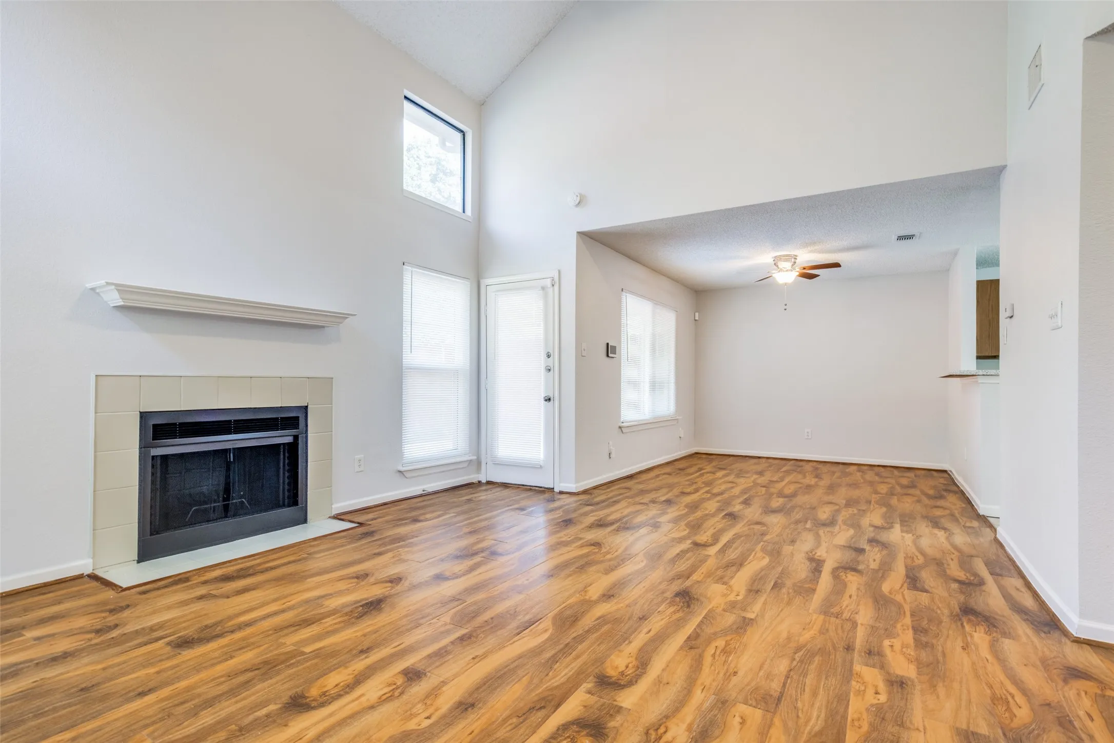 Vaulted ceilings, wood-finish flooring, and a tile-surround fireplace with mantel