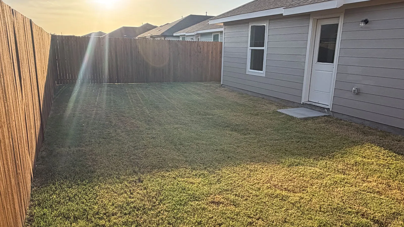 Private backyard with wood fencing, a grass lawn, and light gray horizontal siding