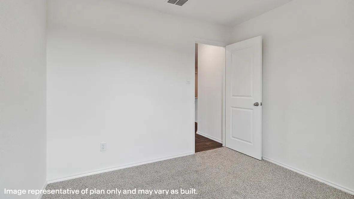 Bright secondary bedroom featuring neutral wall finishes, carpeted flooring, and a white six-panel interior door with brushed nickel hardware