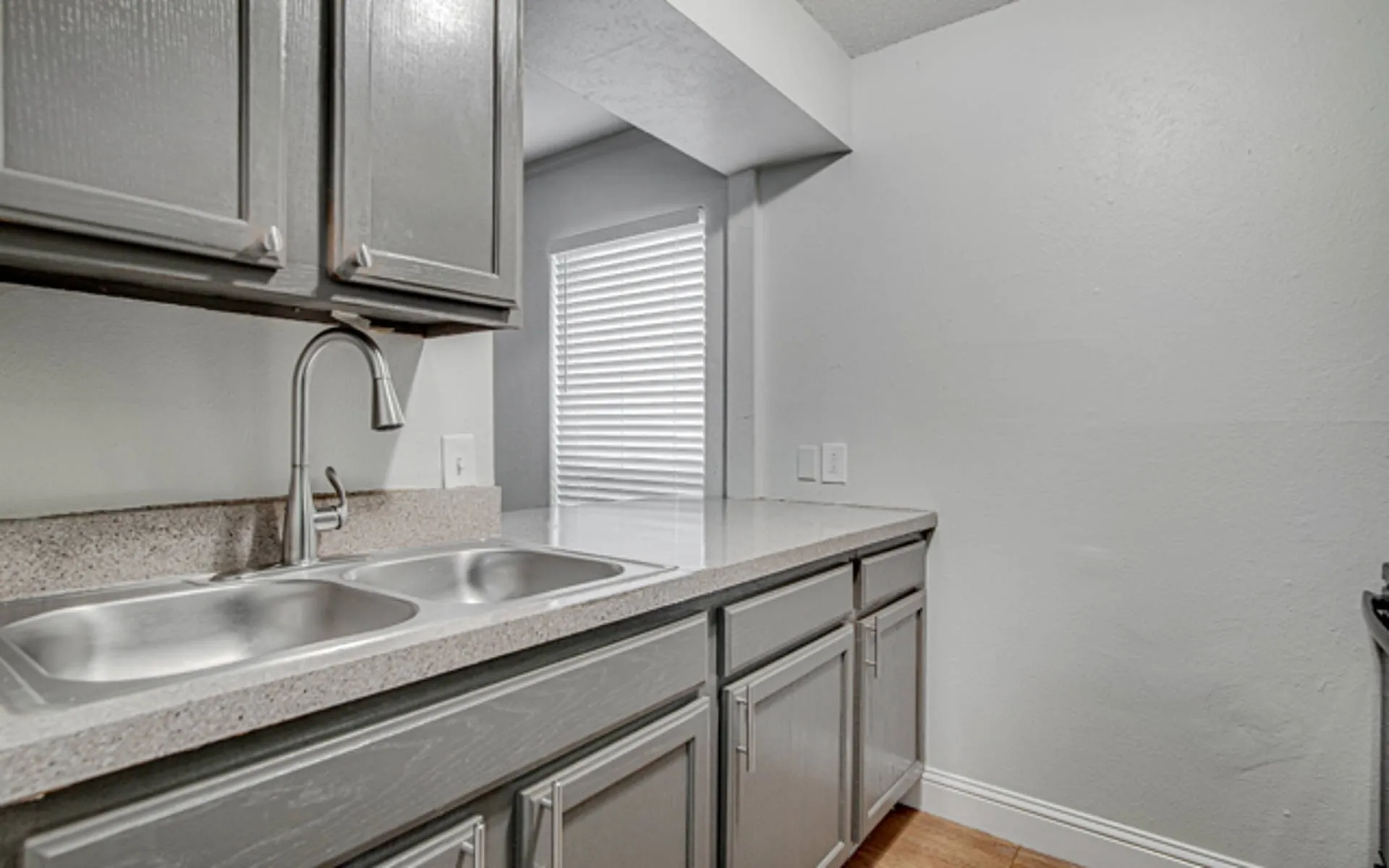 Dual basin stainless steel sink with a high-arch faucet, set into a light-toned countertop