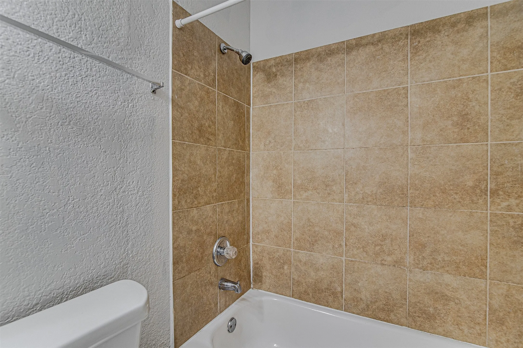 Bathtub with tiled surround, wall-mounted showerhead, and coordinated faucet