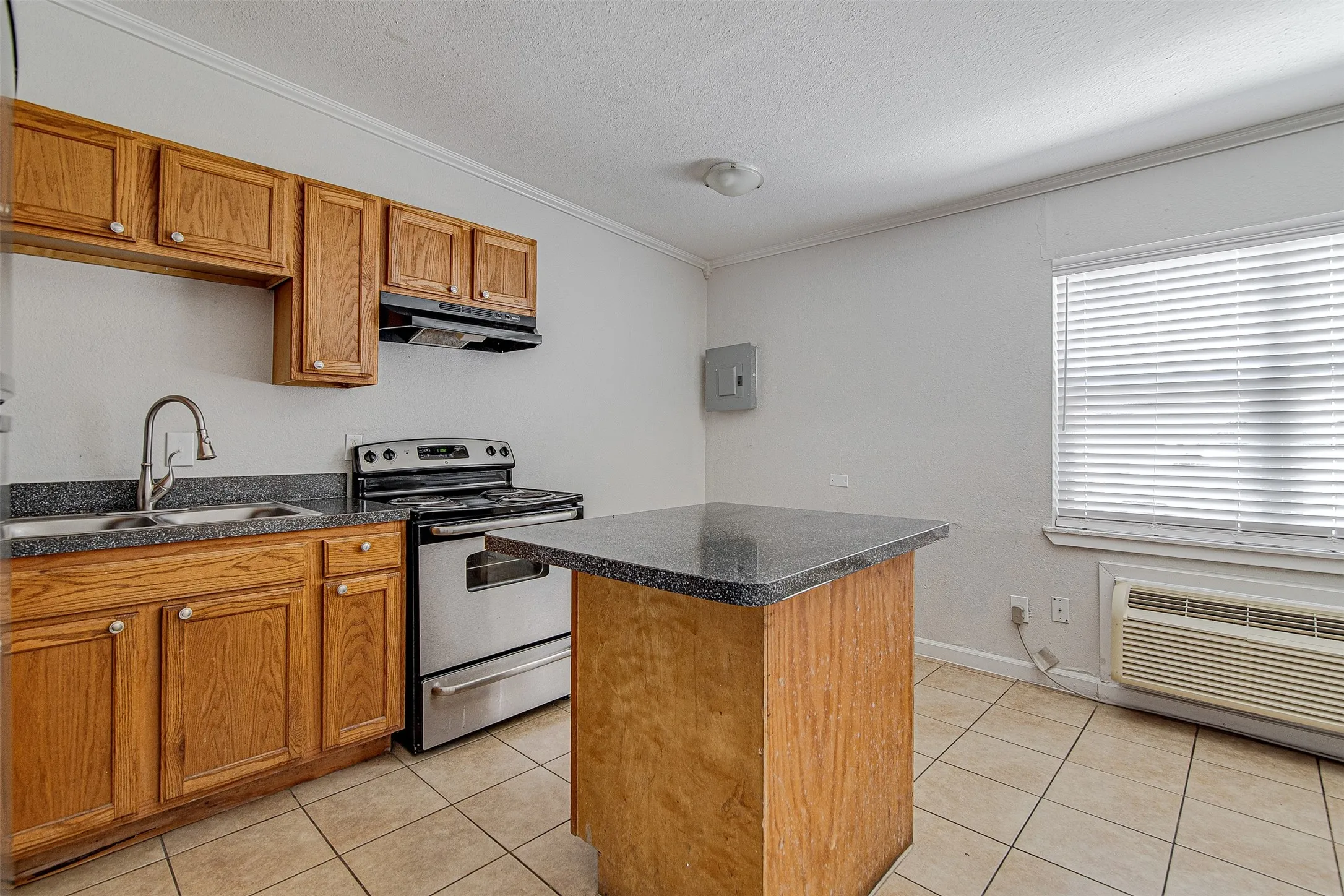 Kitchen featuring wood cabinetry, stainless steel range, and tile flooring