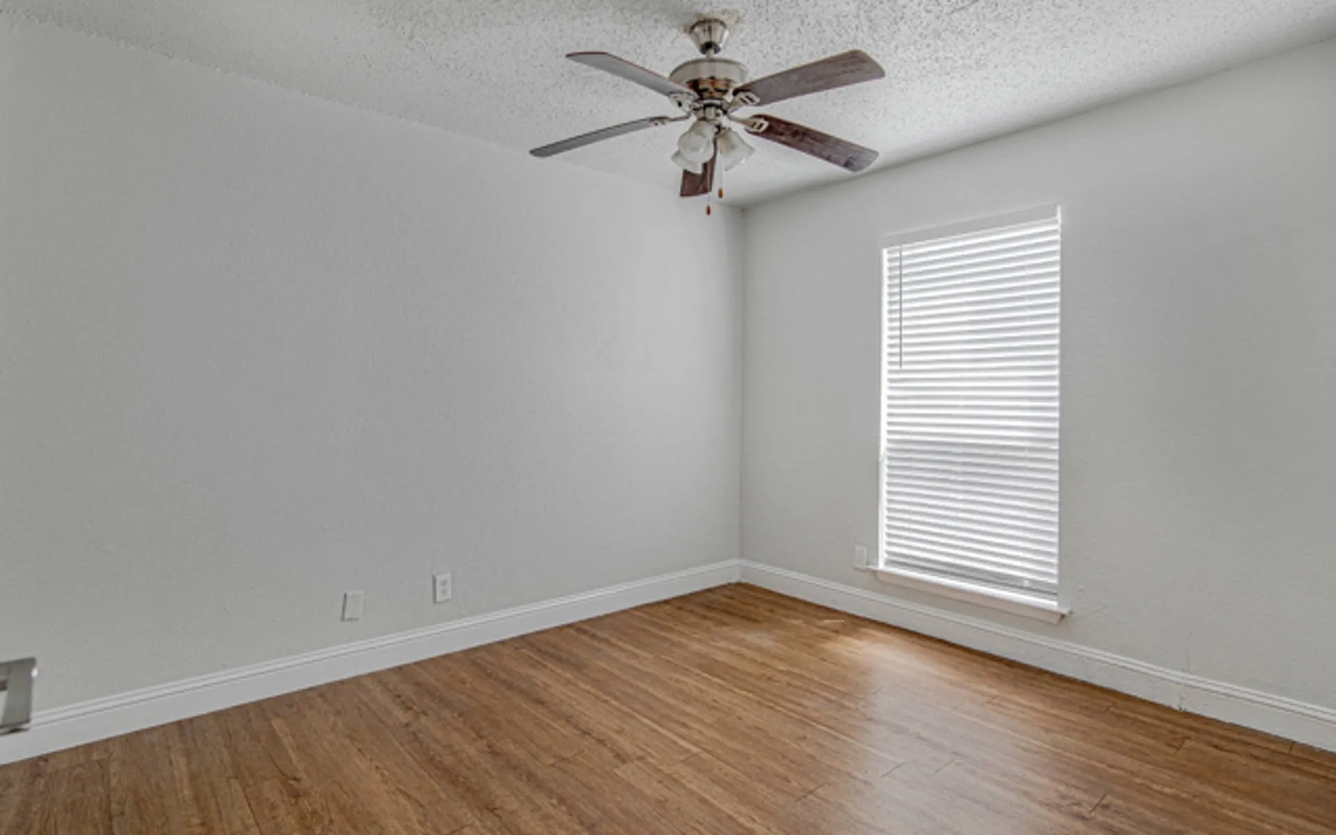 Wood-finish flooring, ceiling fan with light fixture, window with blinds