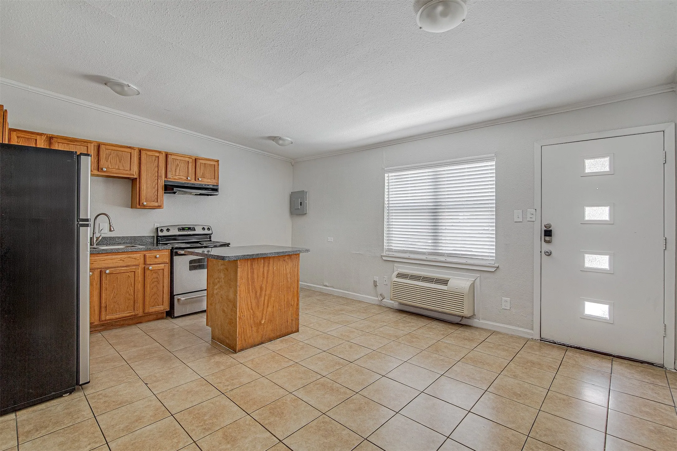 Kitchenette featuring wood cabinetry, stainless steel range, and tile flooring