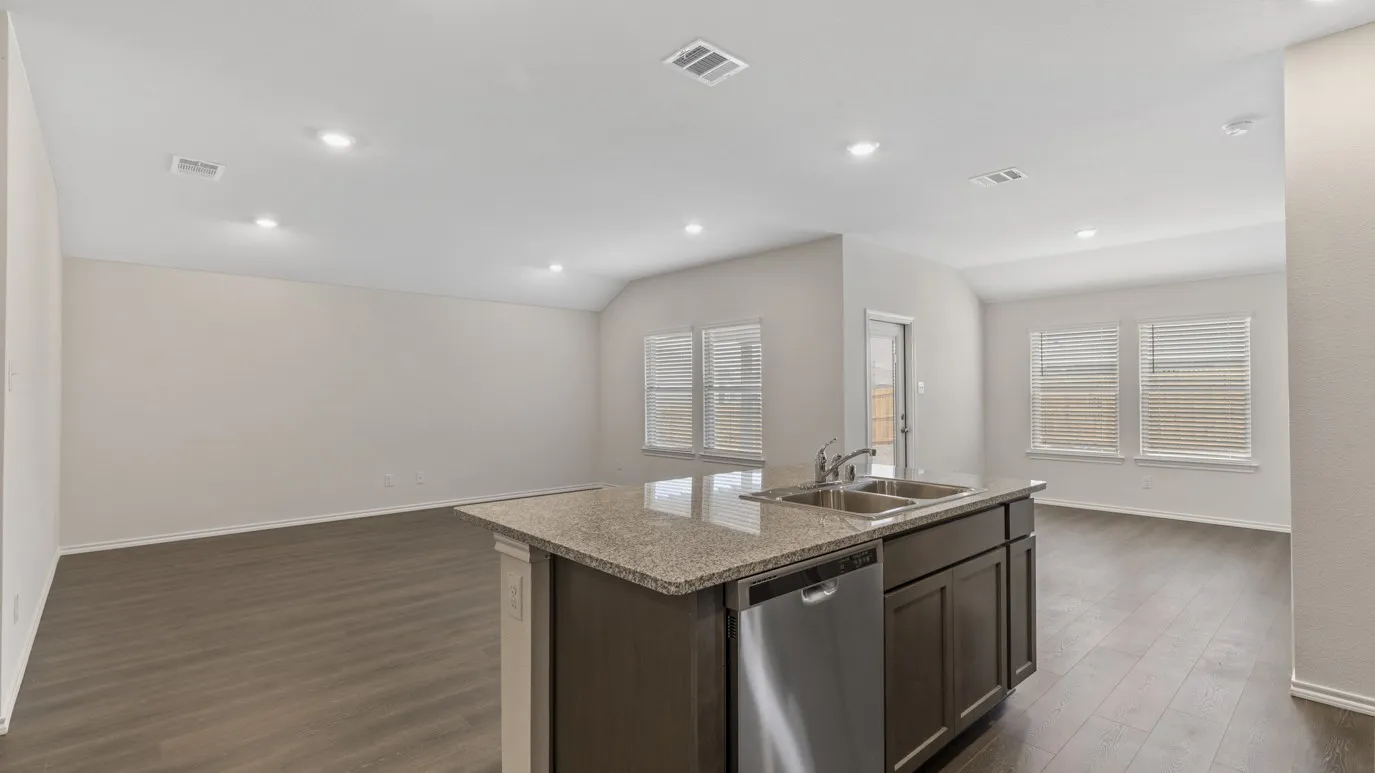 Kitchen island with stone countertop, double stainless steel sink, and integrated dishwasher
