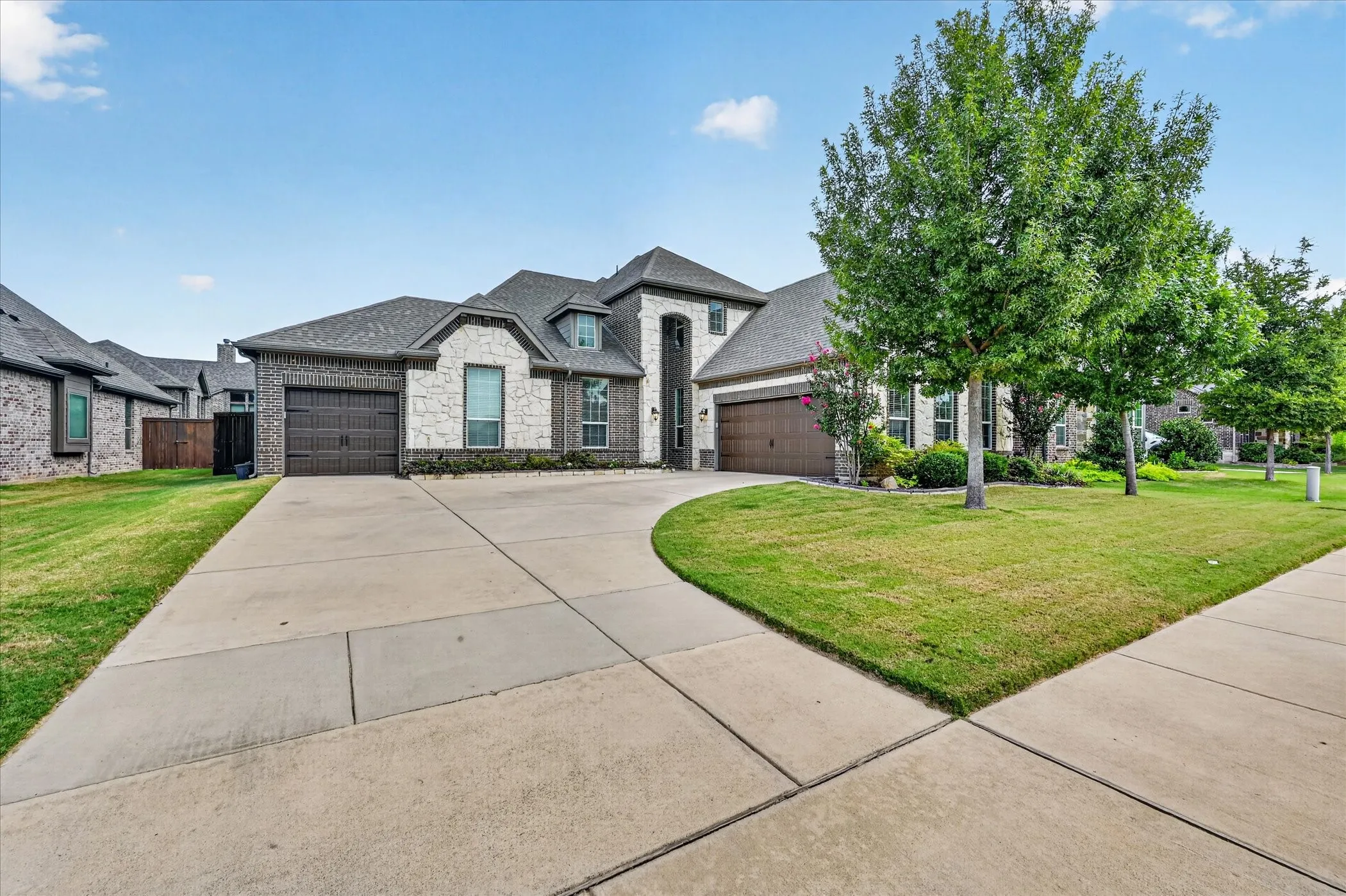 Striking Contemporary home featuring a clean-lined brick and stone exterior, rounded turret detail, and a spacious concrete driveway