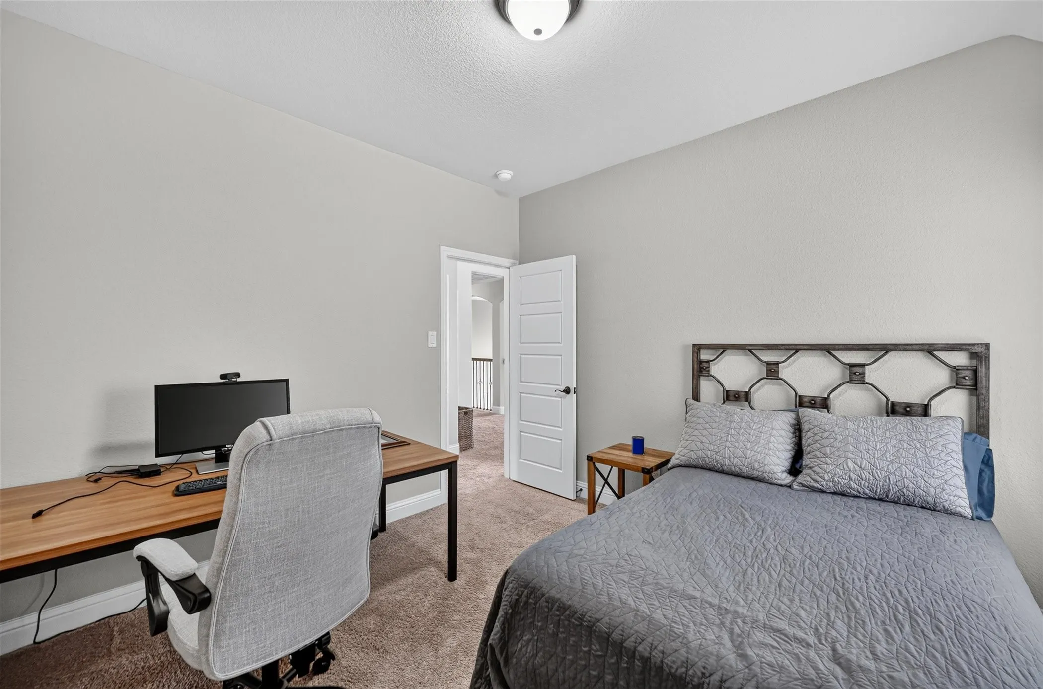 Versatile bedroom featuring neutral wall finishes, carpeted flooring, and a decorative metal headboard