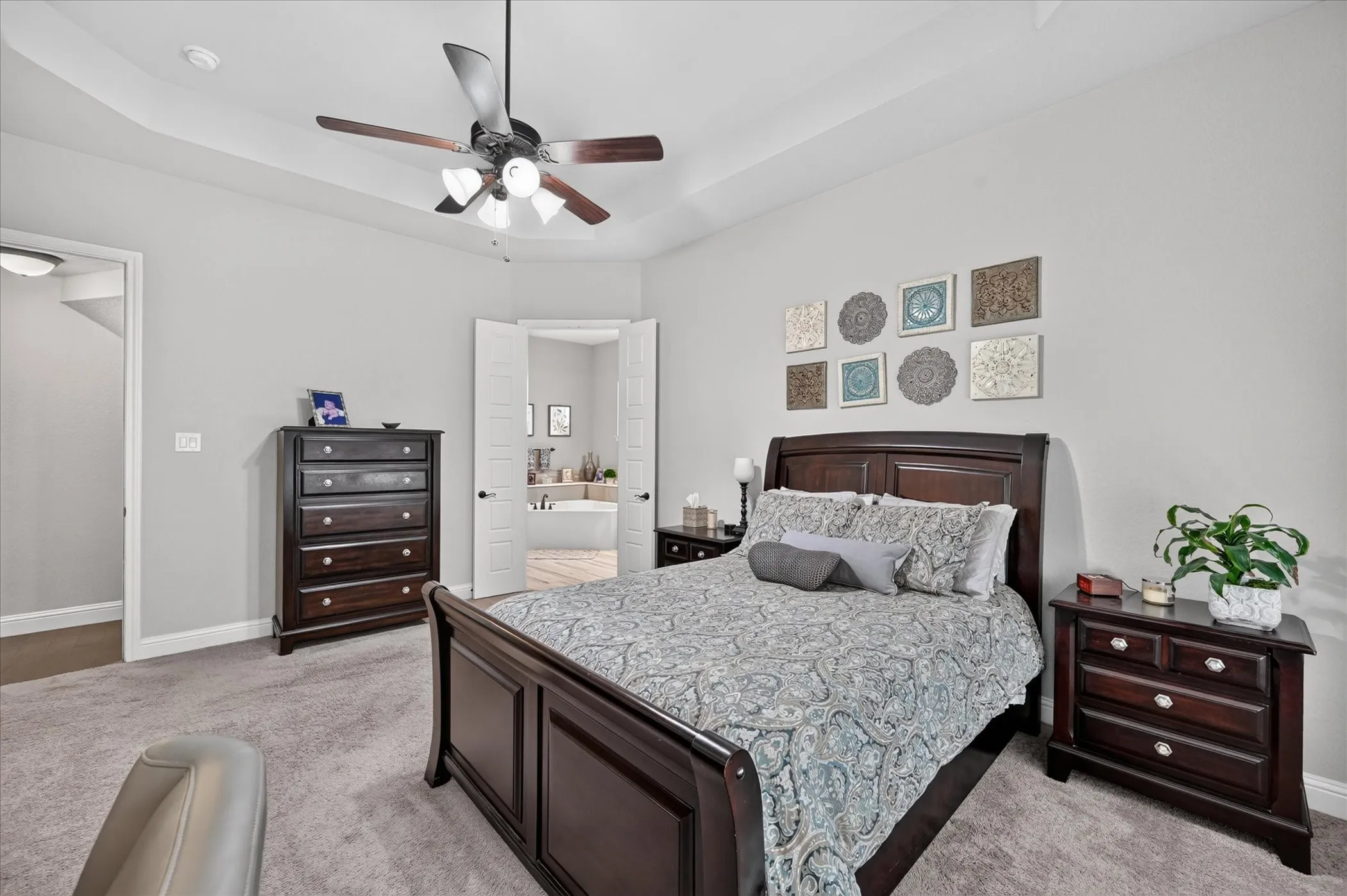 Spacious primary bedroom featuring dark wood furnishings, crisp white bedding, and soft carpet flooring throughout