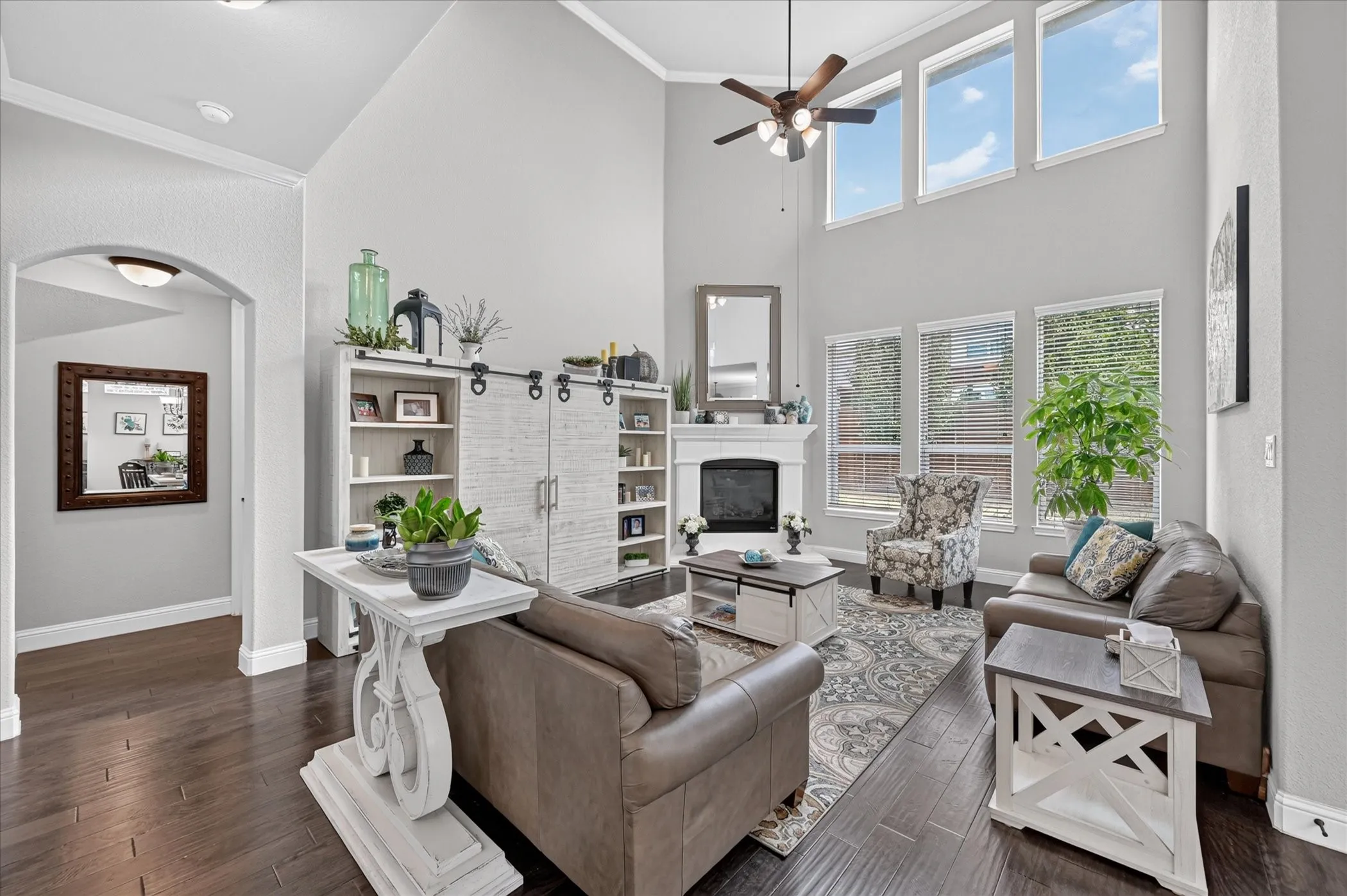 Vaulted ceiling with an attached ceiling fan, floor-to-ceiling windows, dark wood-finish flooring, and a fireplace with a mantel