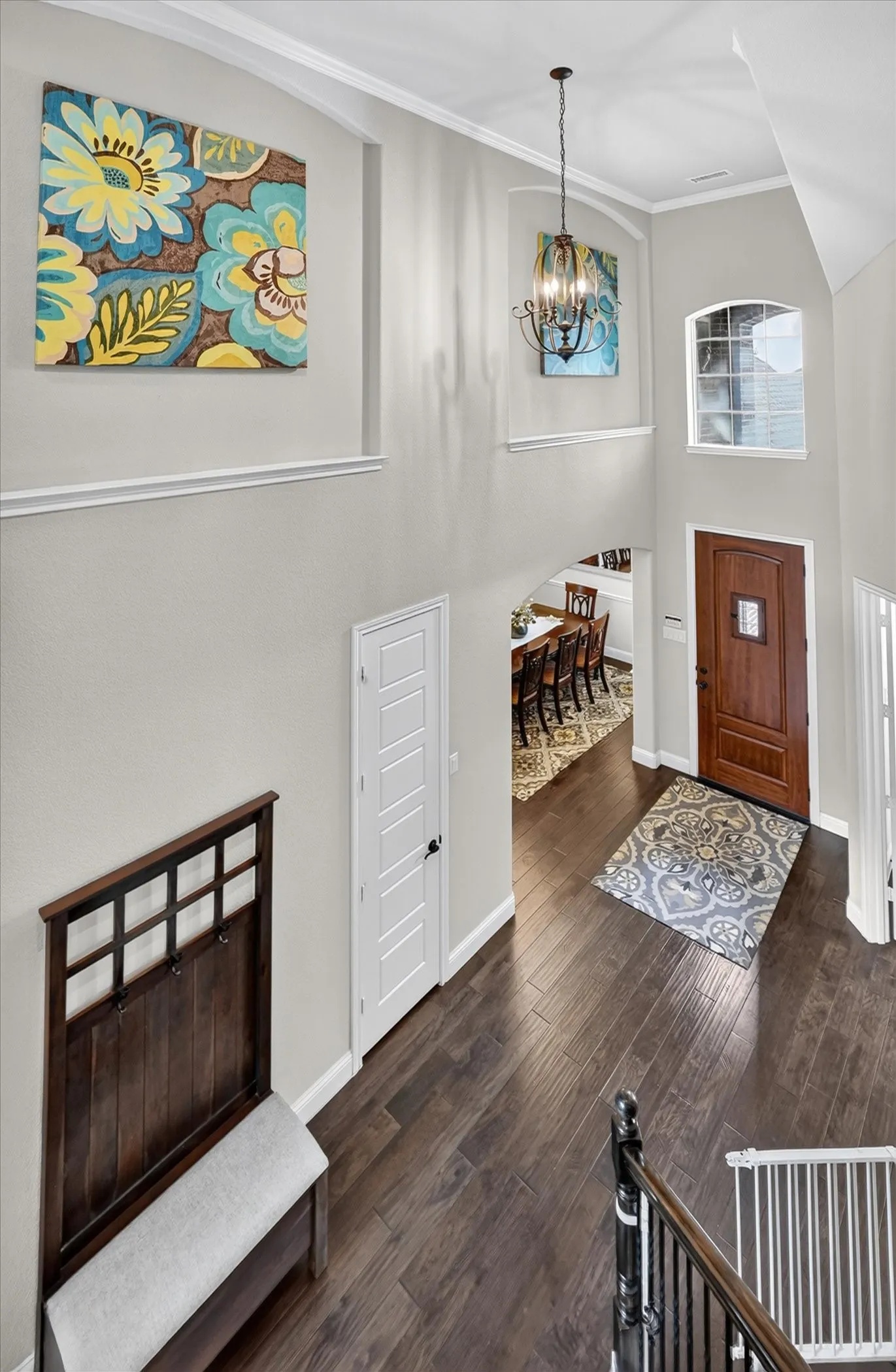 Elegant foyer showcasing dark wood-finish flooring, crisp white wainscoting with chair rail detailing, and soft natural light from transom window