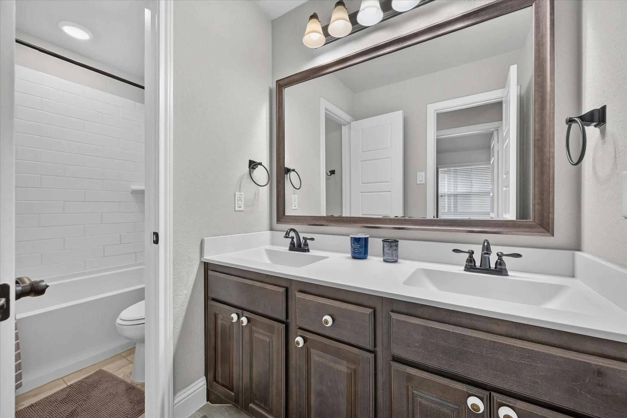 Double vanity with white countertops, dark wood-finish cabinetry, and matte black fixtures