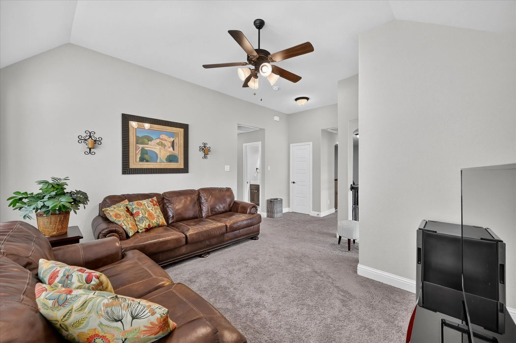 Spacious great room with vaulted ceiling and ceiling fan, complemented by wood-finish flooring throughout