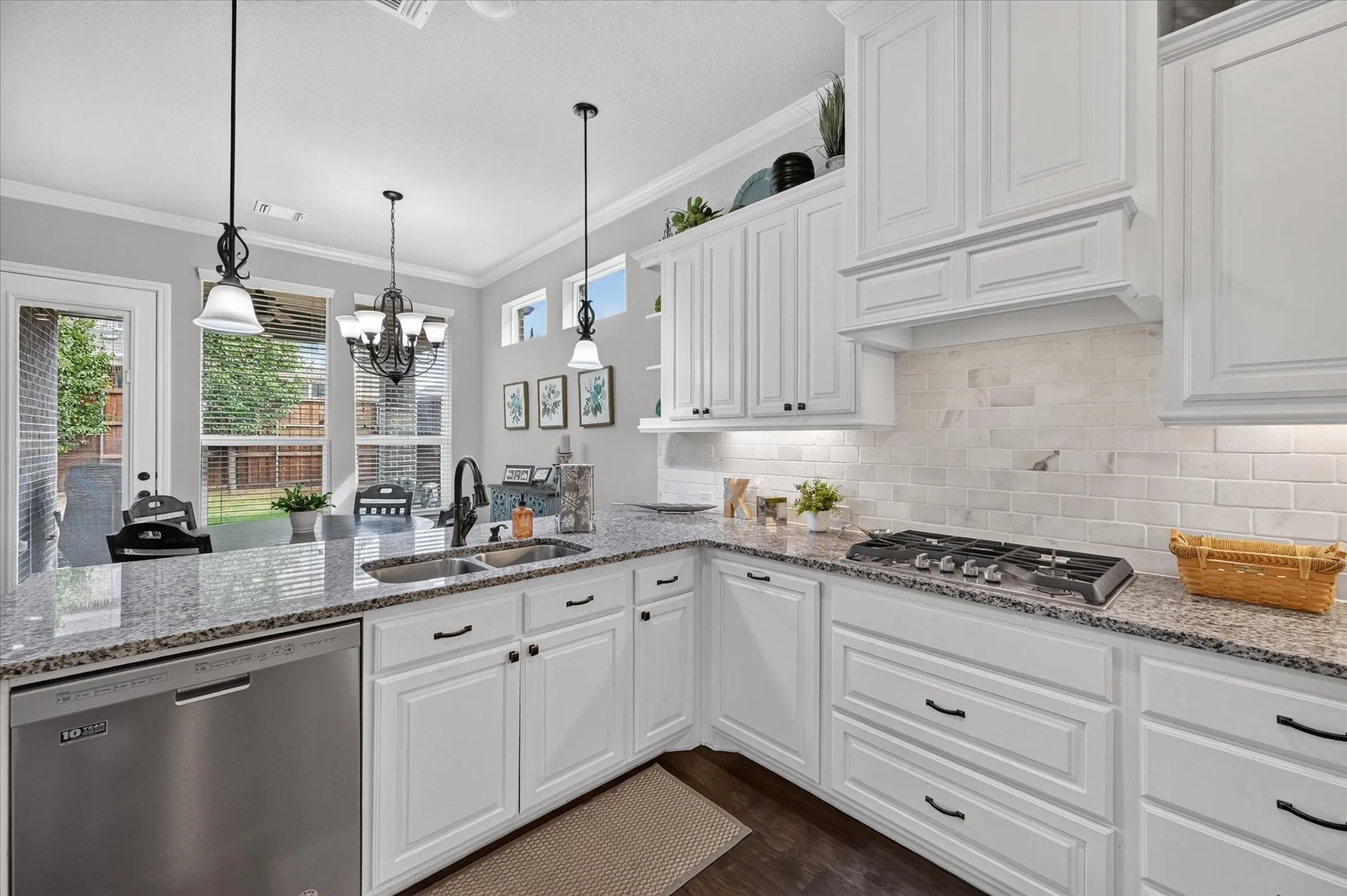 Chef's kitchen featuring white cabinetry with hardware accents, granite countertops, subway tile backsplash, and stainless steel appliances including a gas cooktop and dishwasher