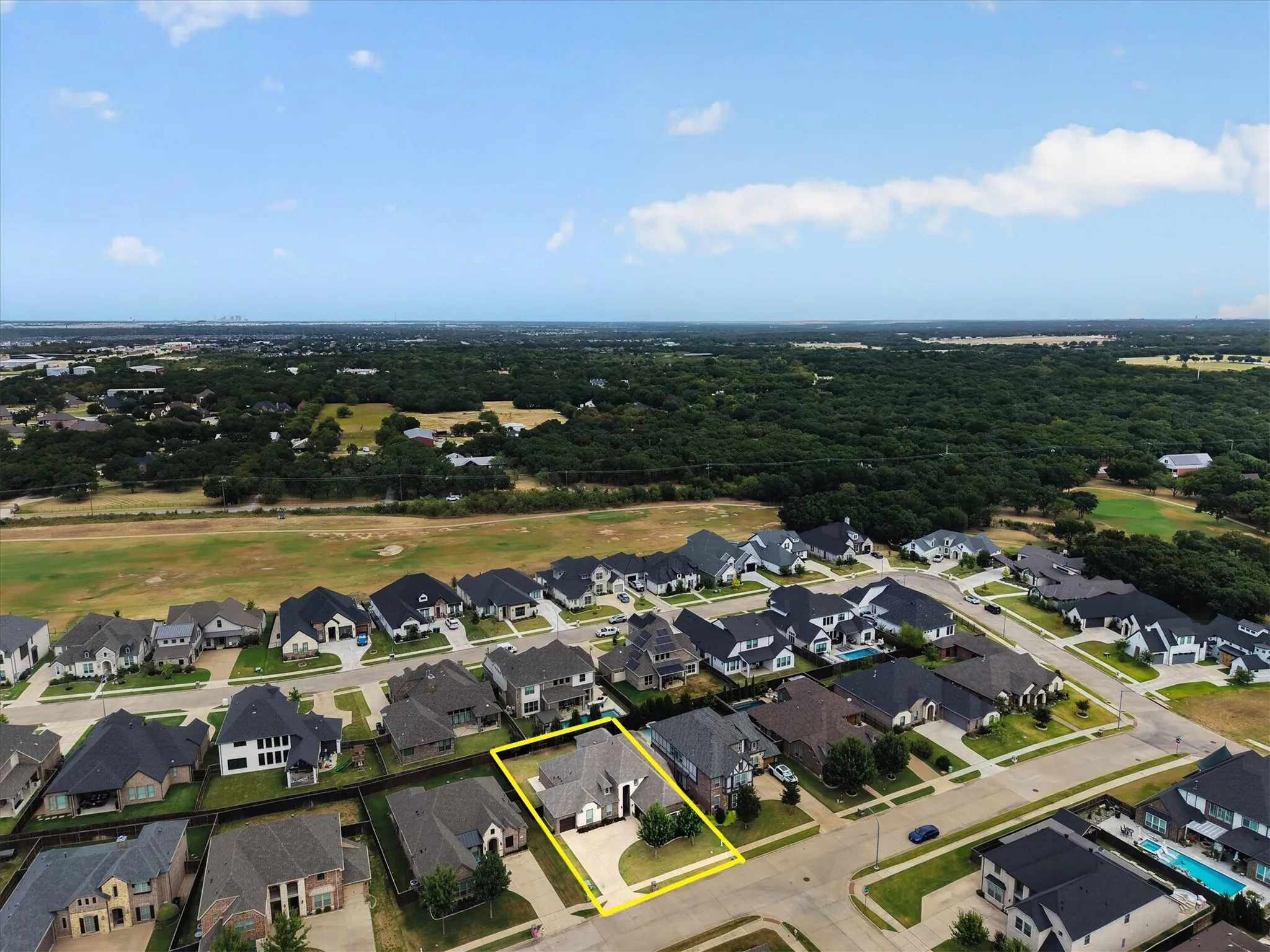 Aerial view of a newly developed residential community featuring multiple custom homes with distinctive architectural styles, manicured lawns, and professional landscaping