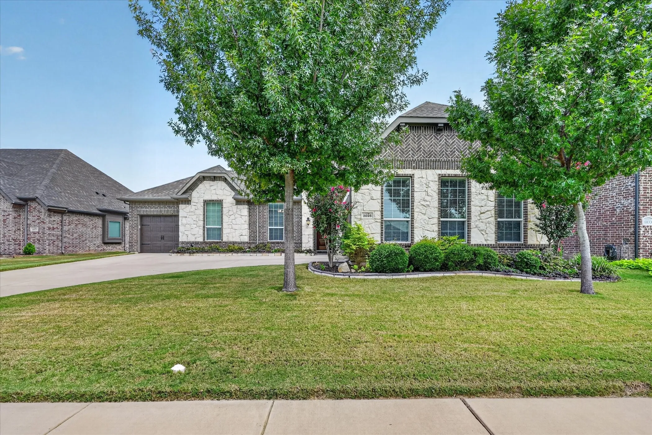 Elegant brick residence with a distinctive cupola-topped design, complemented by manicured lawn, mature shade trees, and a circular driveway
