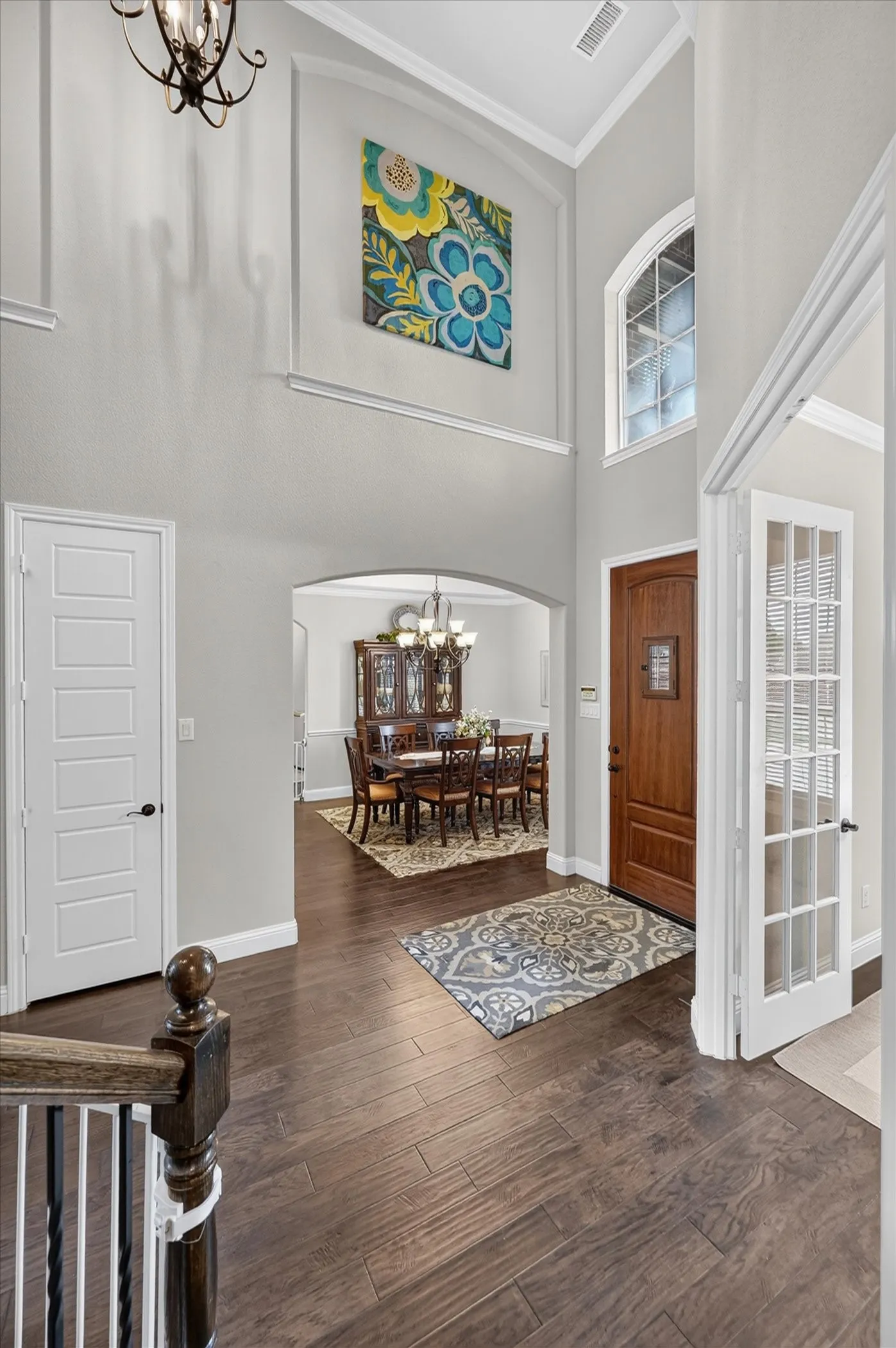 Welcoming foyer showcasing soaring ceilings, dark wood-finish flooring, and an arched entryway leading to the formal dining area