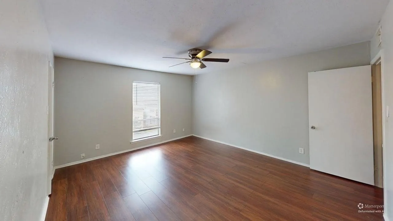 Wood-finish flooring with a ceiling fan and window with blinds