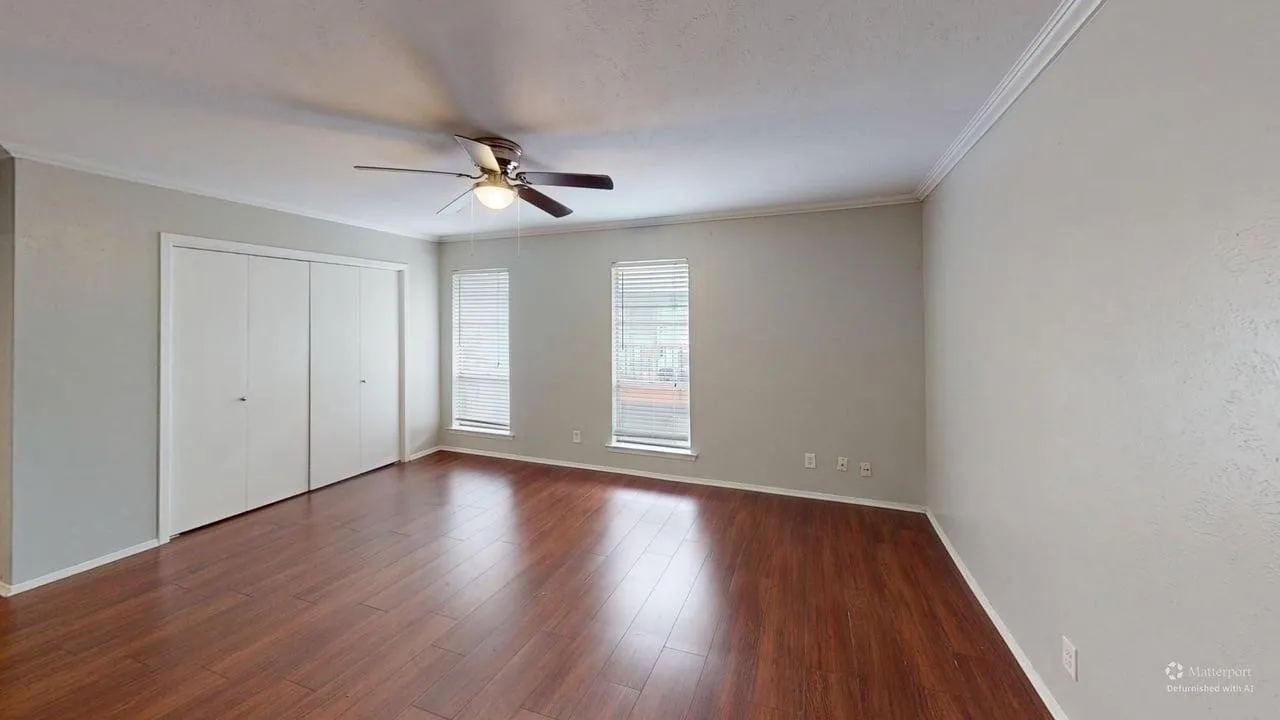 Wood-finish flooring, two windows with blinds, a ceiling fan with integrated lighting, and crown molding