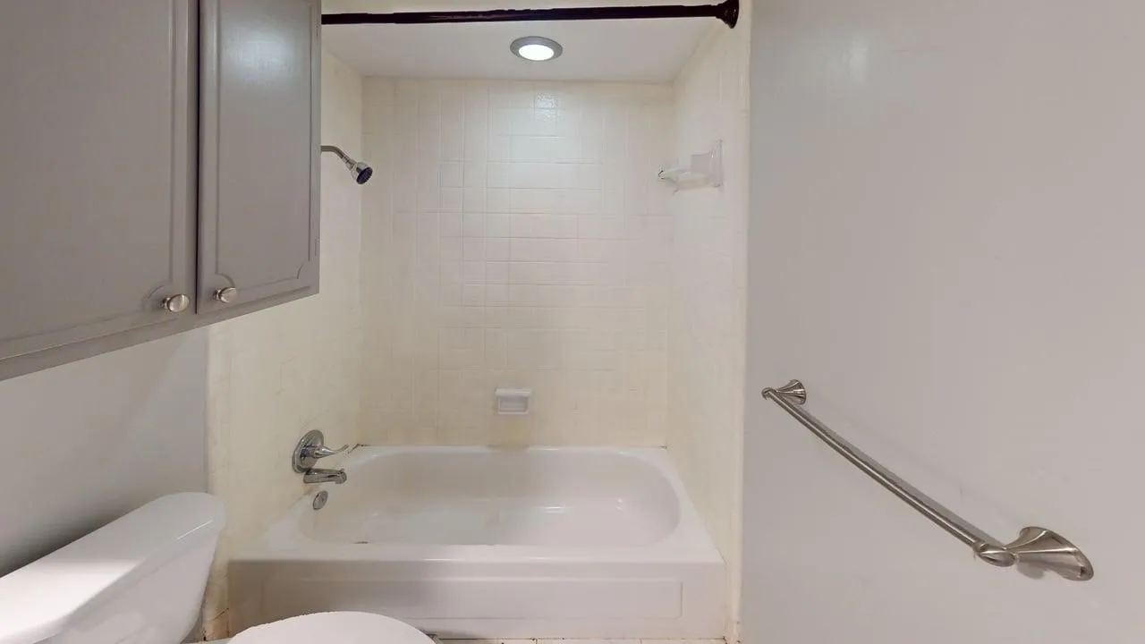 White tiled shower/tub combination with a wall-mounted showerhead and faucet