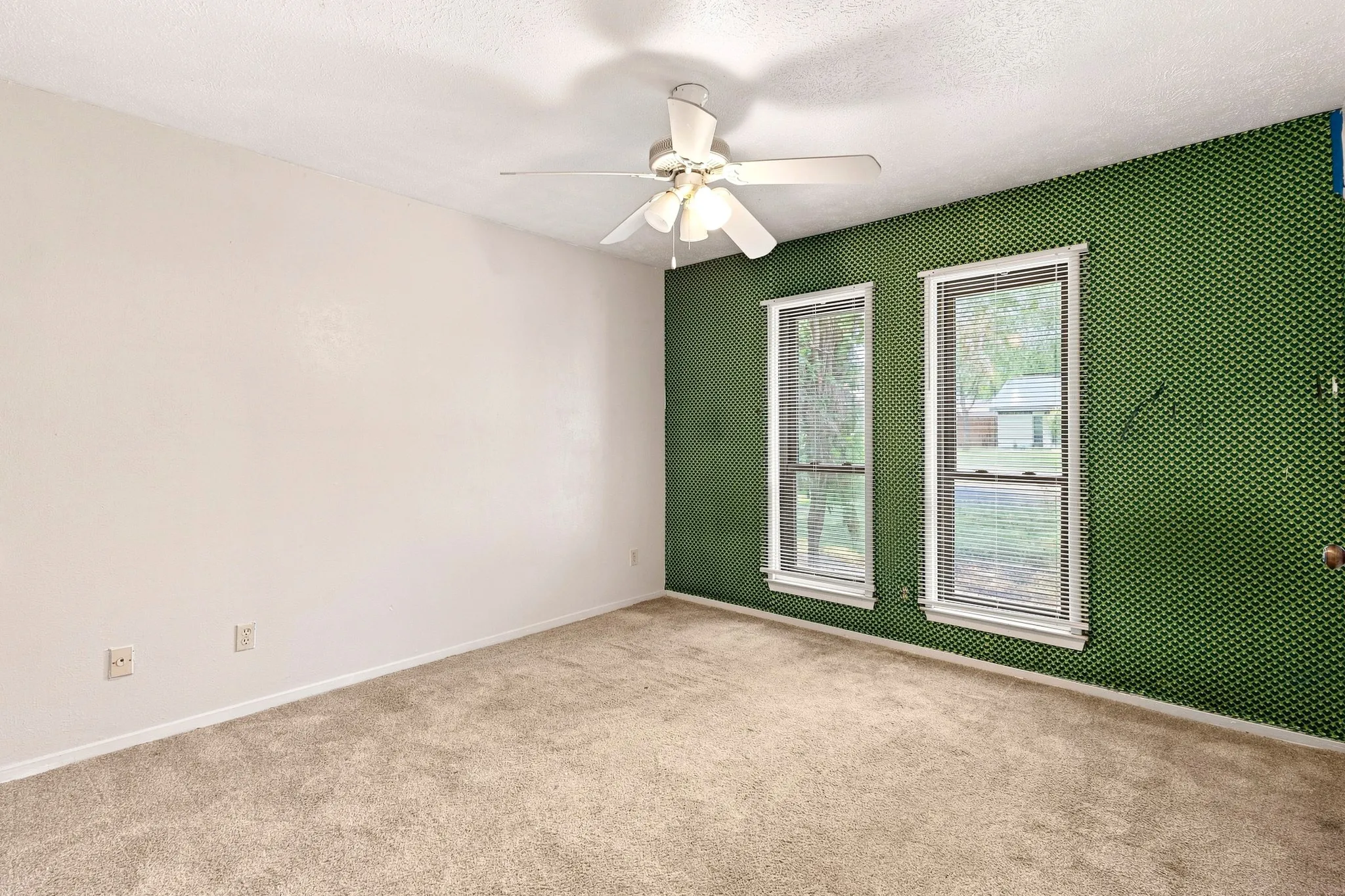Wall-to-wall carpeting, two single-hung windows, a ceiling fan, and a textured ceiling