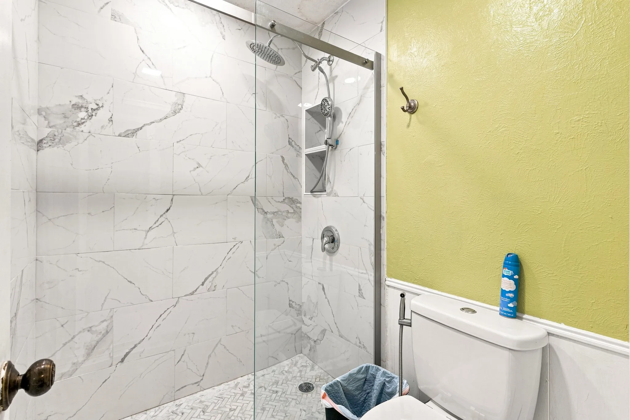 Glass-enclosed shower with a rainfall showerhead, tiled walls, and built-in shelving