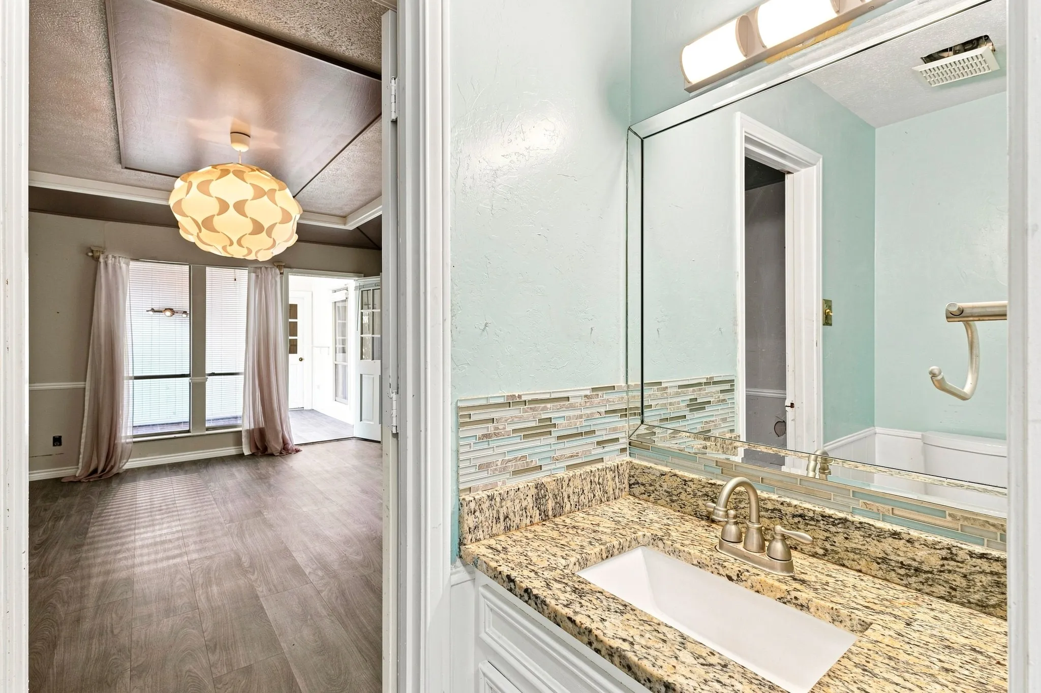 Recessed ceiling detail with a decorative light fixture, wood-finish flooring, and French doors