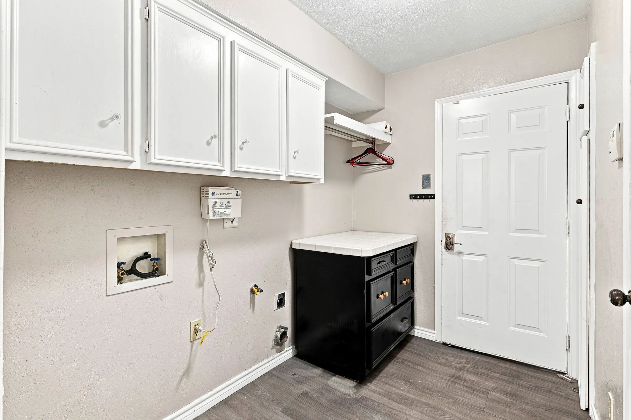 Laundry area featuring upper white cabinetry, a built-in counter with storage, wood-finish flooring, and panel-style doors
