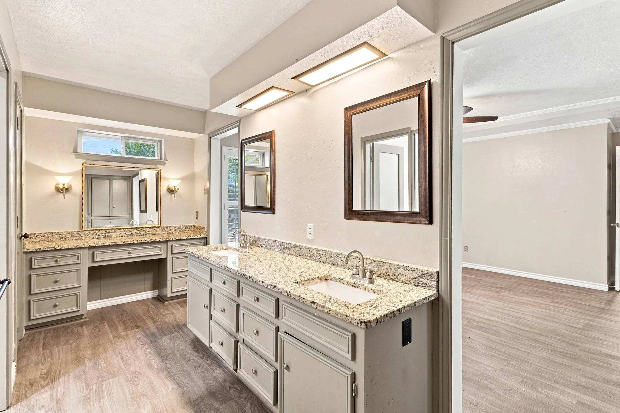 Dual vanity with undermount sinks, stone countertops, wood-finish flooring, and built-in cabinetry