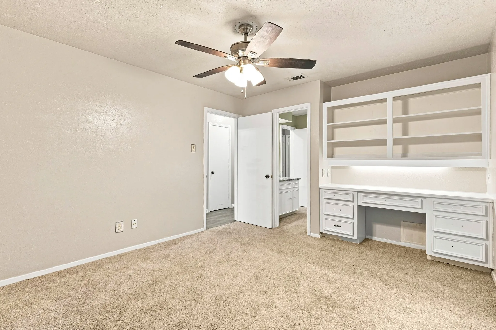 Built-in desk with storage drawers, integrated shelving, and task lighting