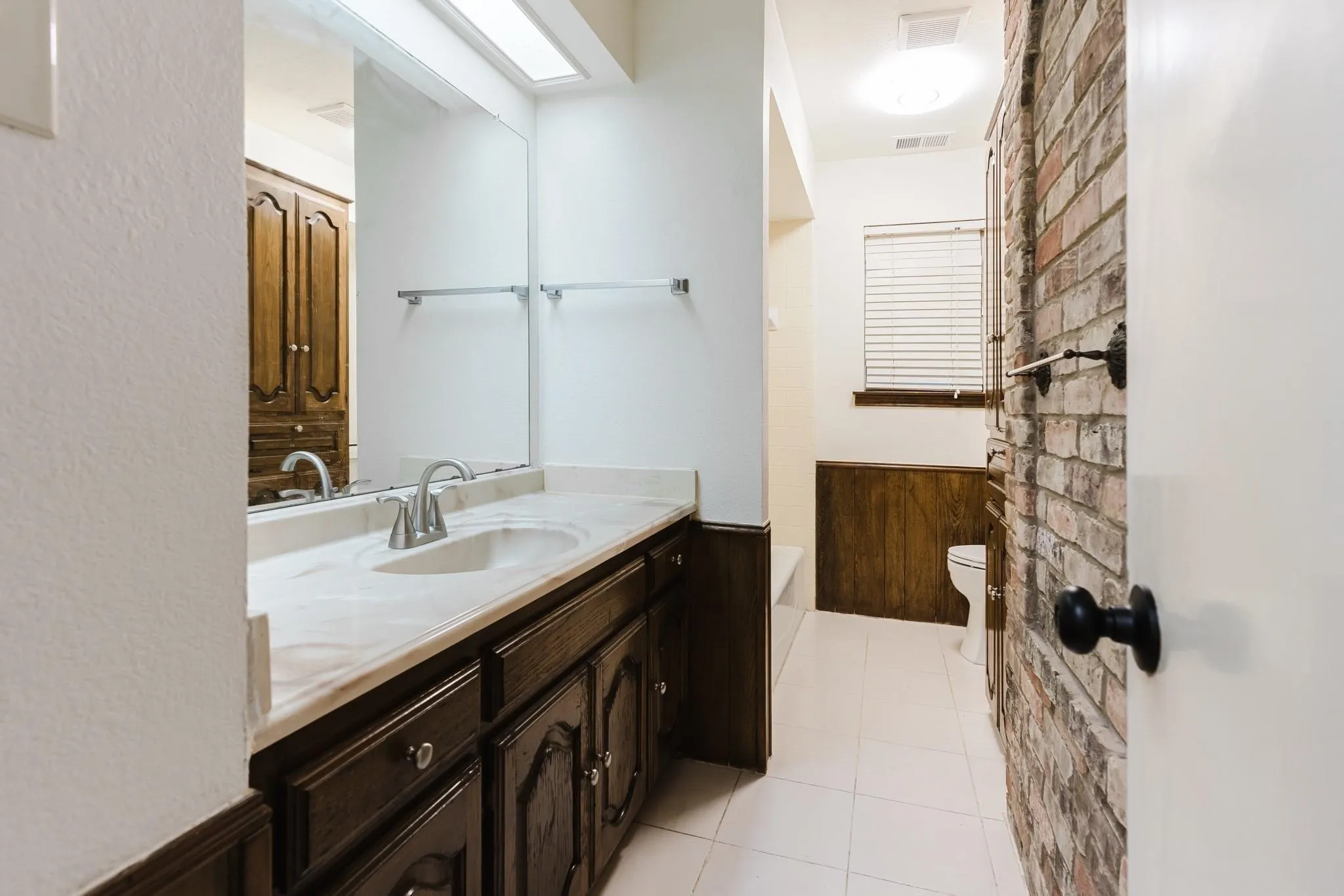 Vanity with a single sink, light-toned countertop, and dark wood-finish cabinetry