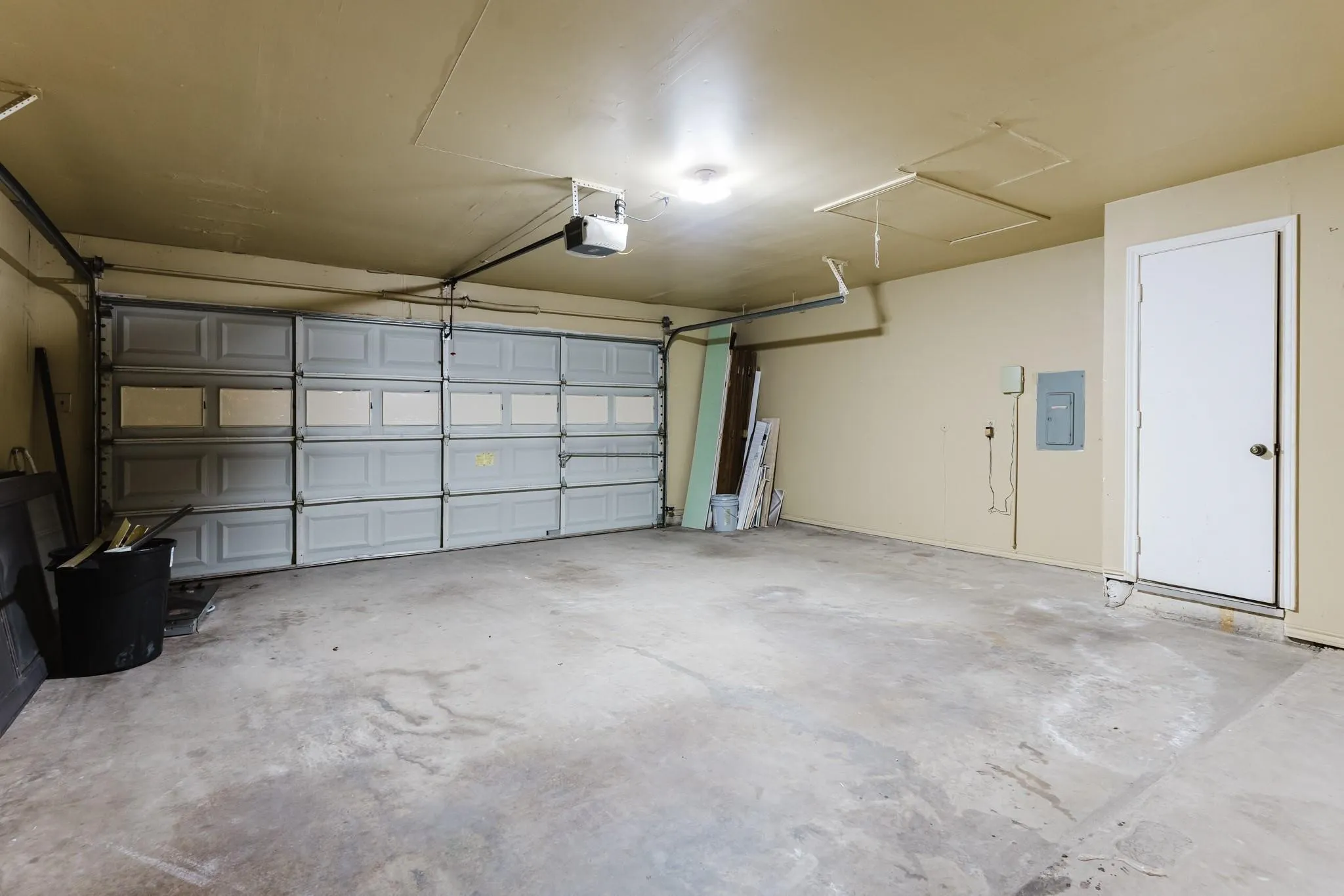 Two-car garage featuring a sectional garage door, concrete flooring, and a single interior access door
