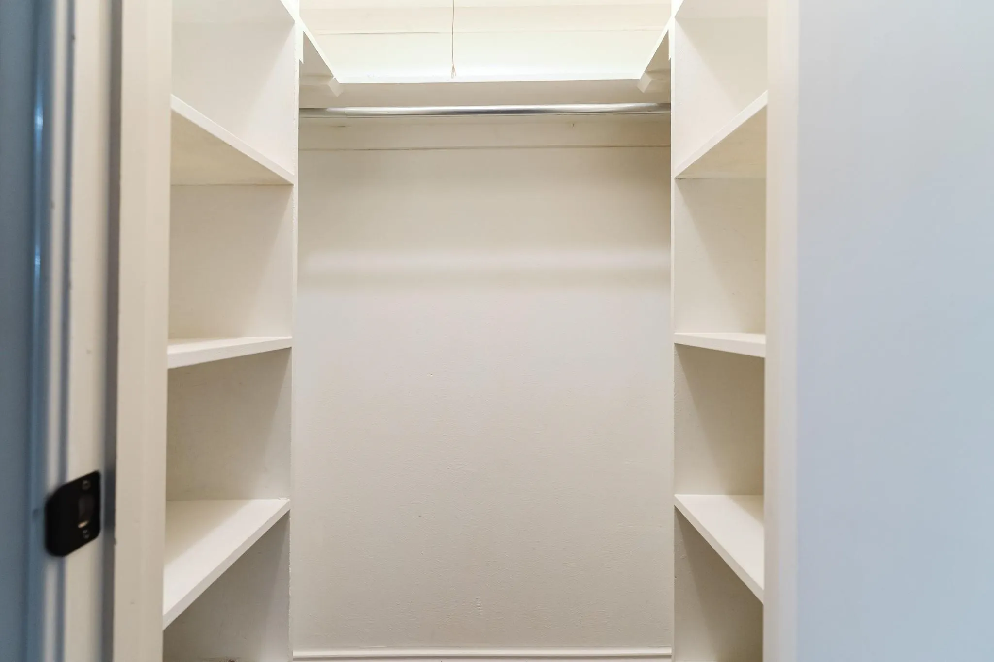 Integrated shelving, chrome hanging rod, and light-toned walls