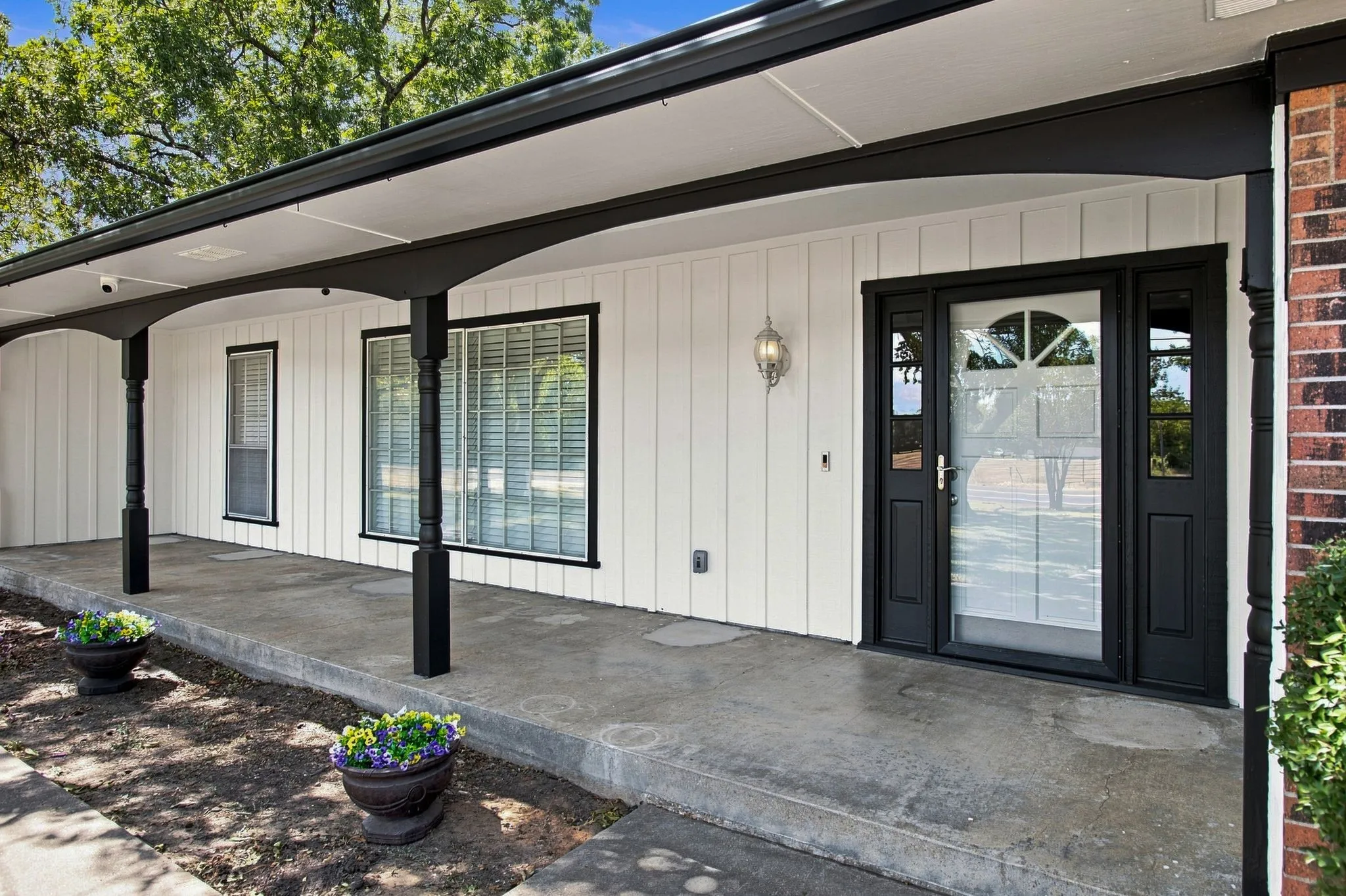 Covered front porch with dark-stained wooden posts