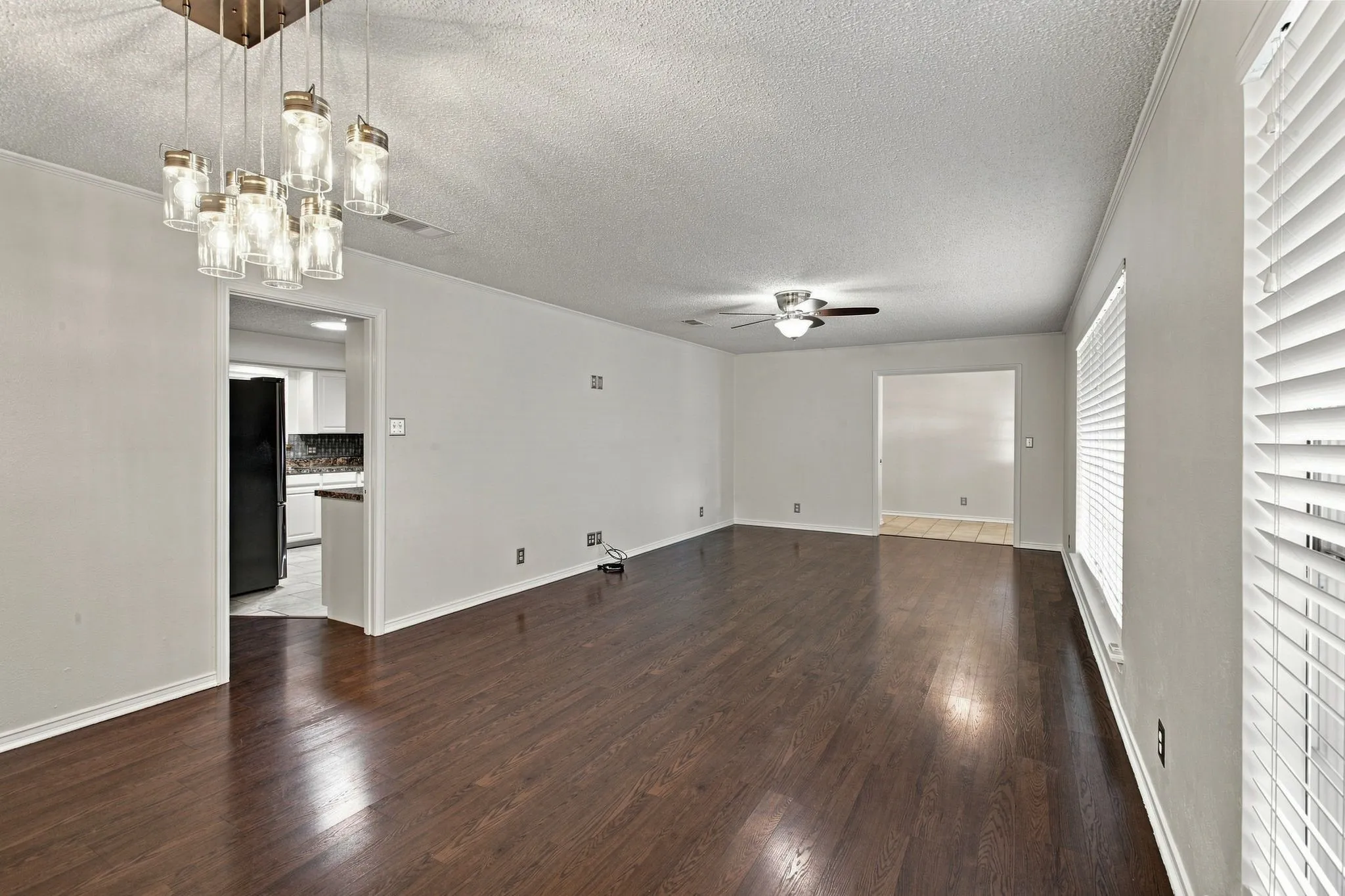 Open concept living space featuring dark wood-finish flooring, and a multi-light chandelier