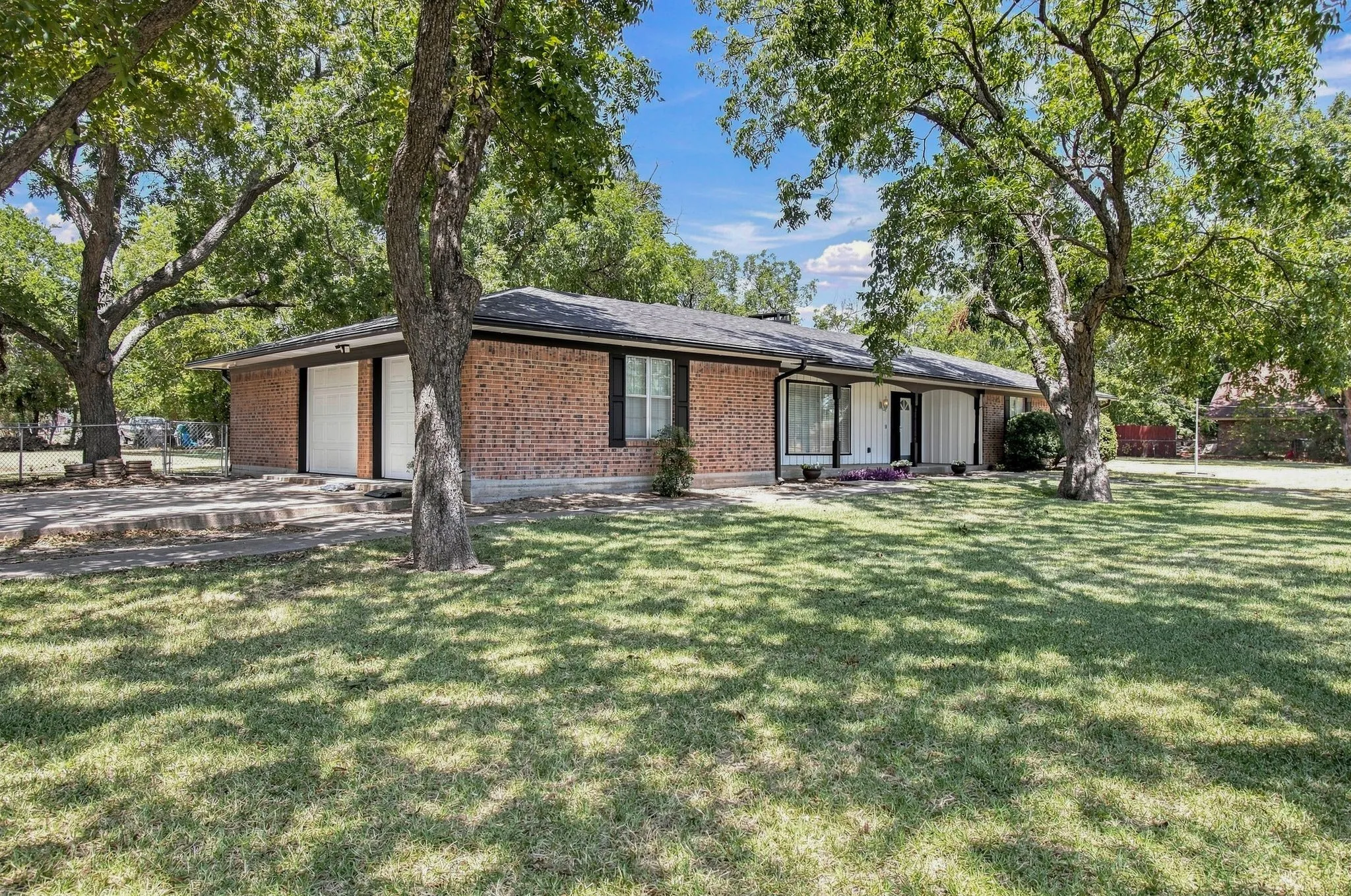Brick exterior, dual side entry garage doors, expansive lawn, mature pecan shade trees, and a covered entry