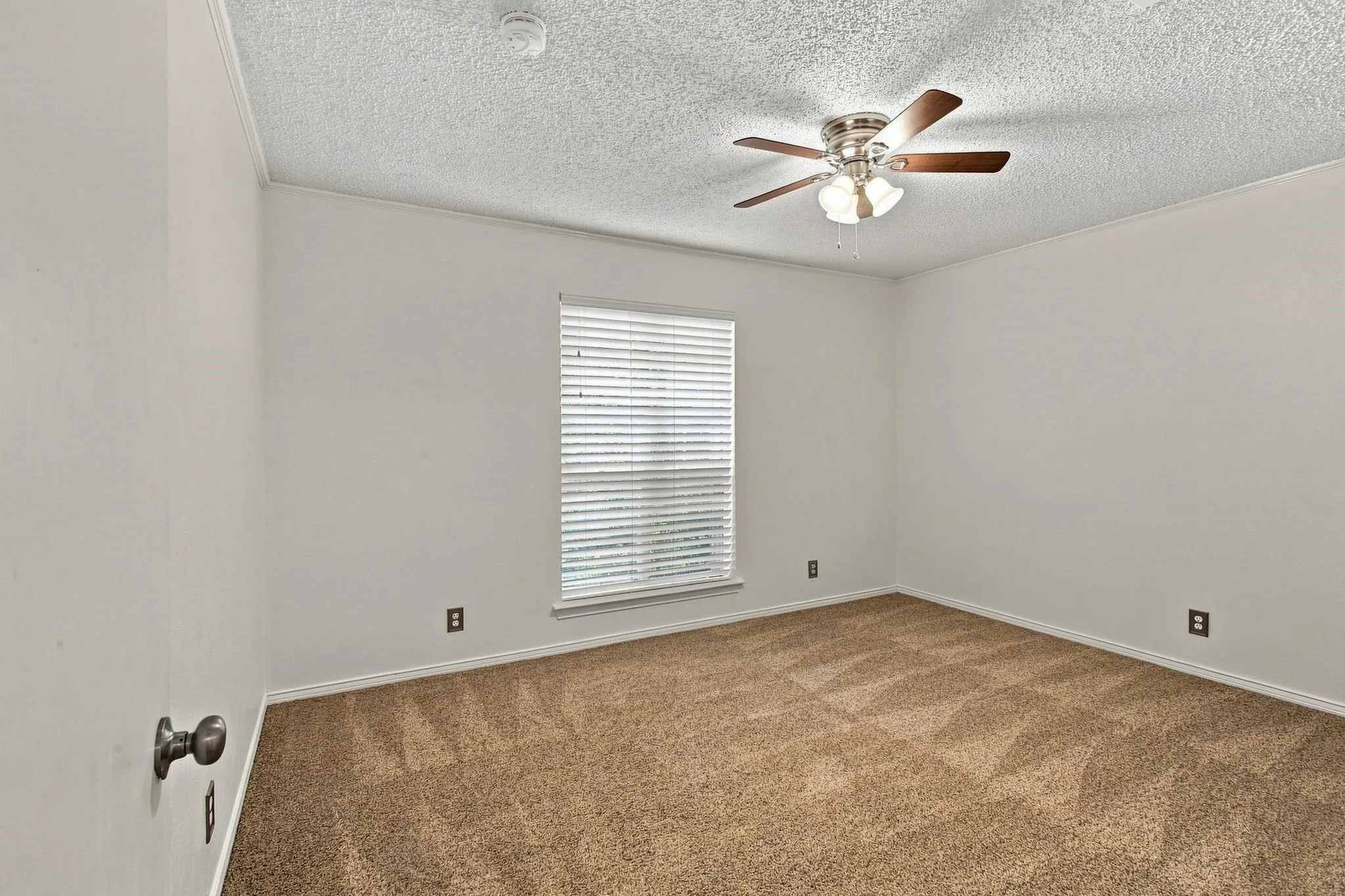 Carpeted room featuring a ceiling fan, a window with blinds
