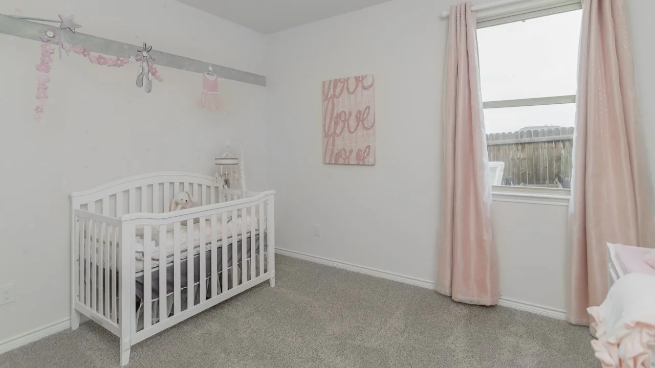 White walls featuring a decorative border, light gray carpet flooring, and a window with a privacy fence visible