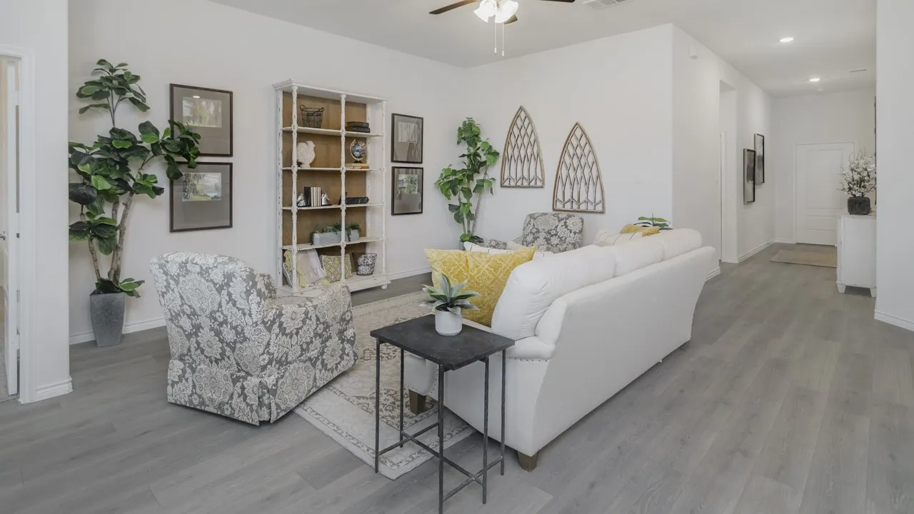 Light gray wood-finish flooring throughout, white walls, built-in shelving, and a ceiling fan with integrated lighting