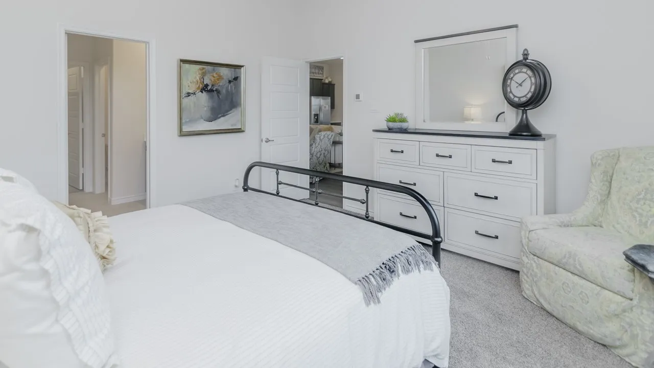 White painted walls, carpeted flooring, and a white dresser with dark hardware